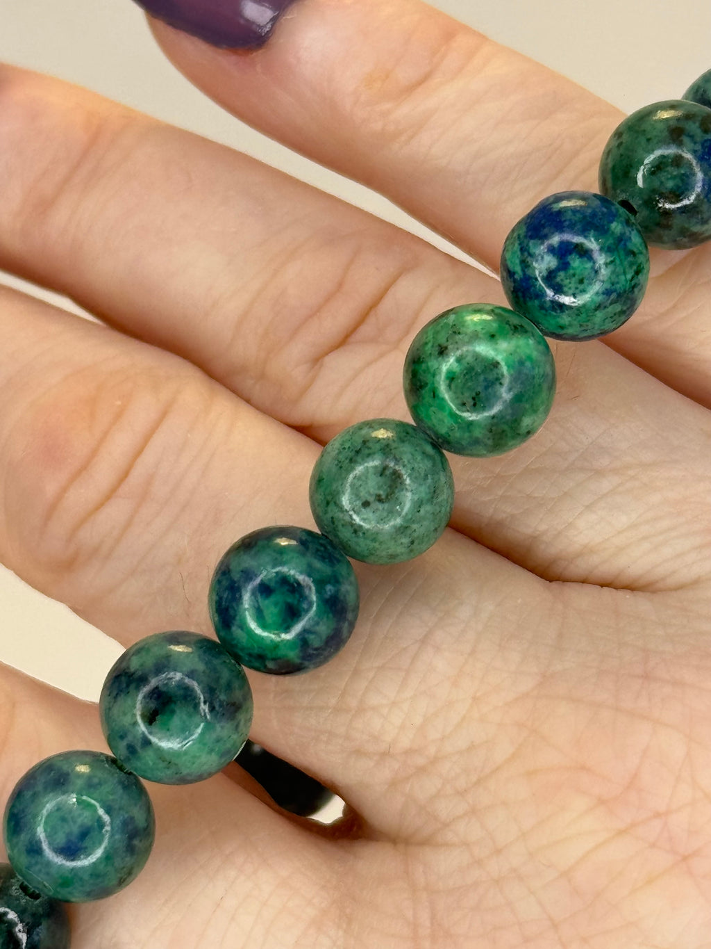 Green beaded bracelet on a hand with a neutral background