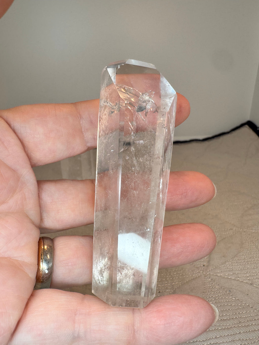 Clear crystal held between fingers against a neutral background