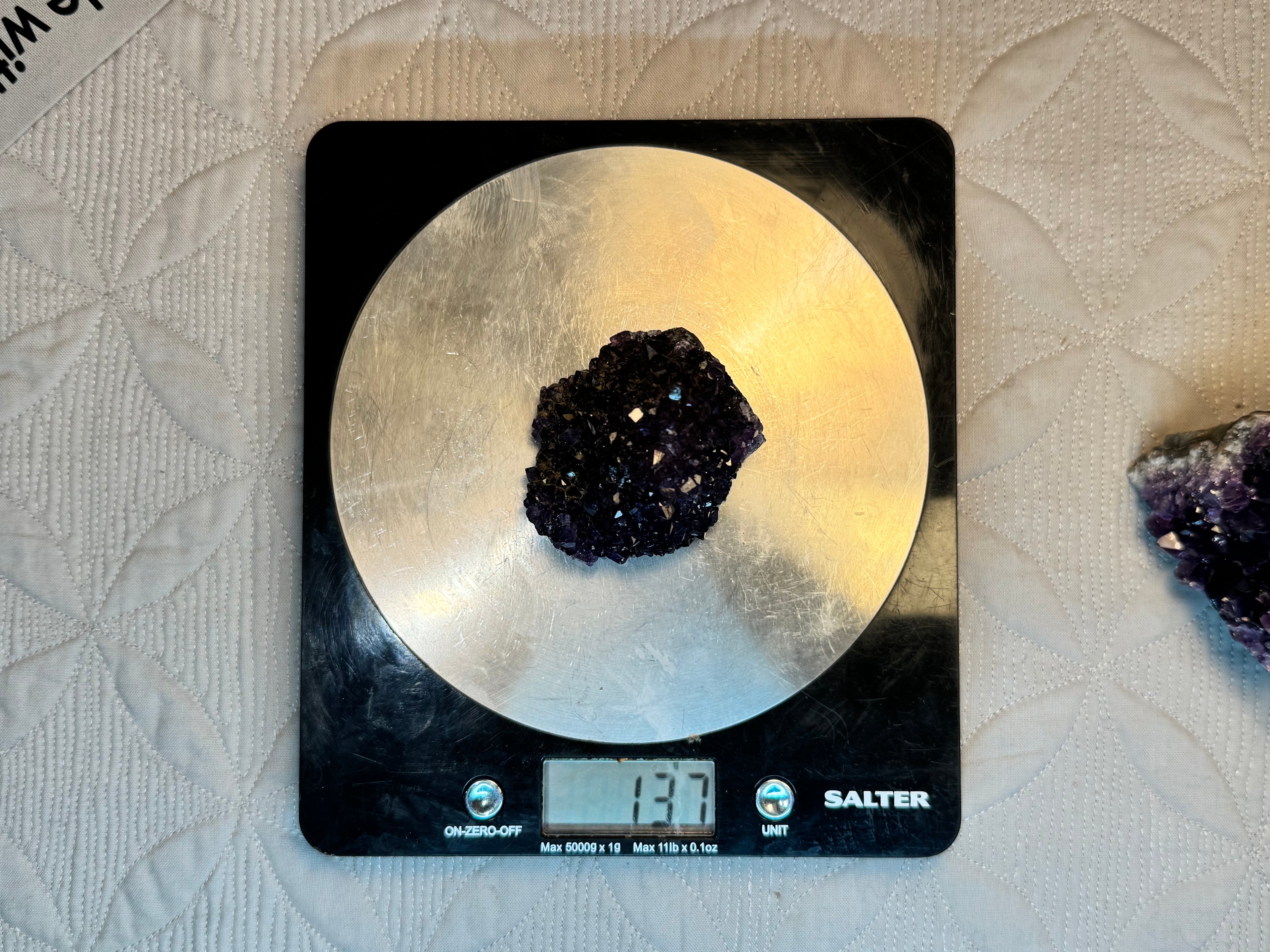 purple crystal on a digital kitchen scale with a white background