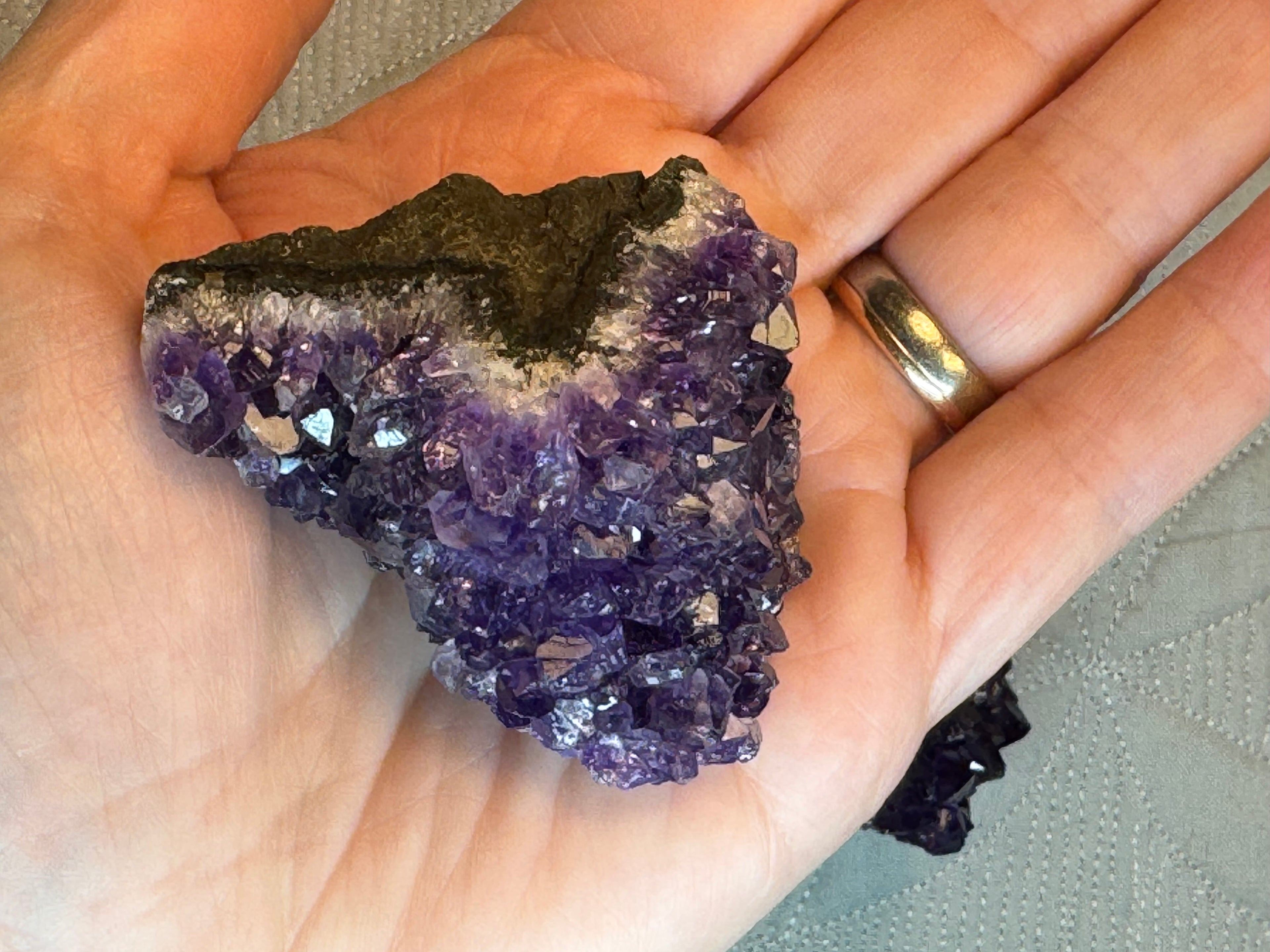 Hand holding a large amethyst crystal with a textured background