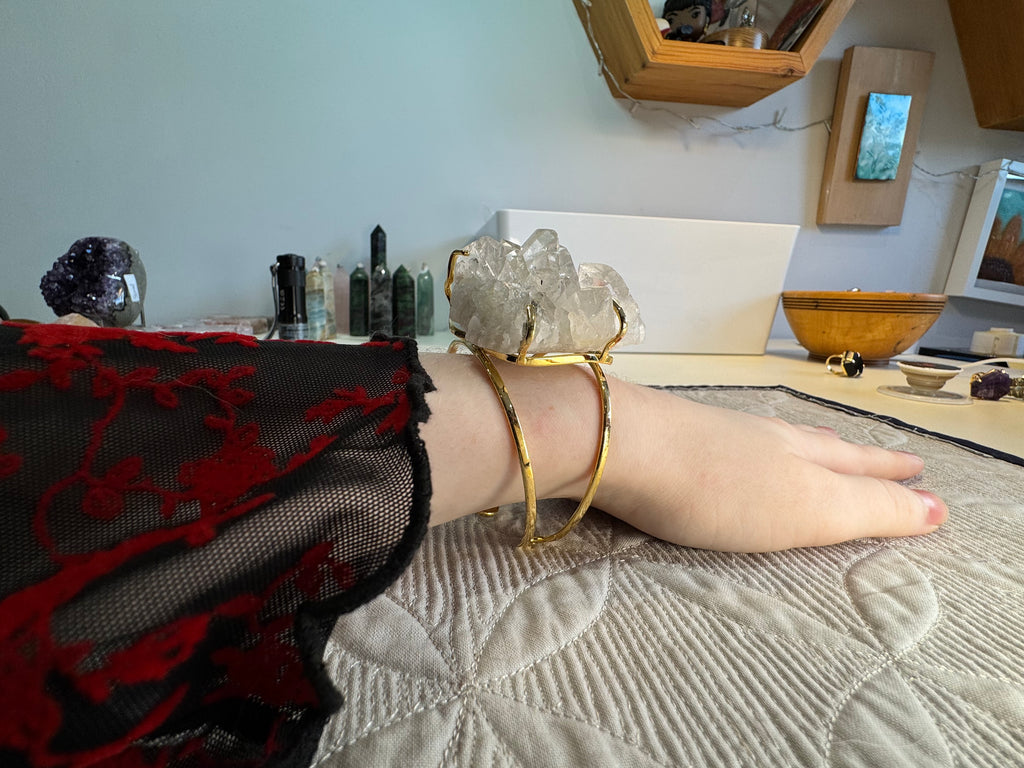 Person wearing a gold bracelet on a textured surface with a blurred background