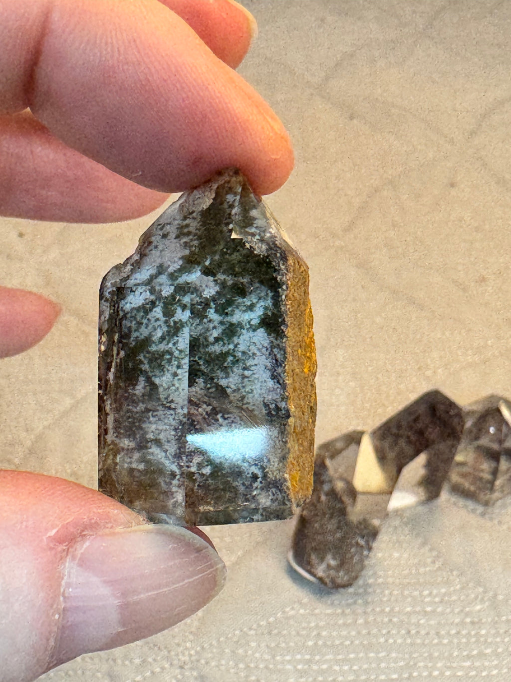 Person holding a rough stone with a beige background