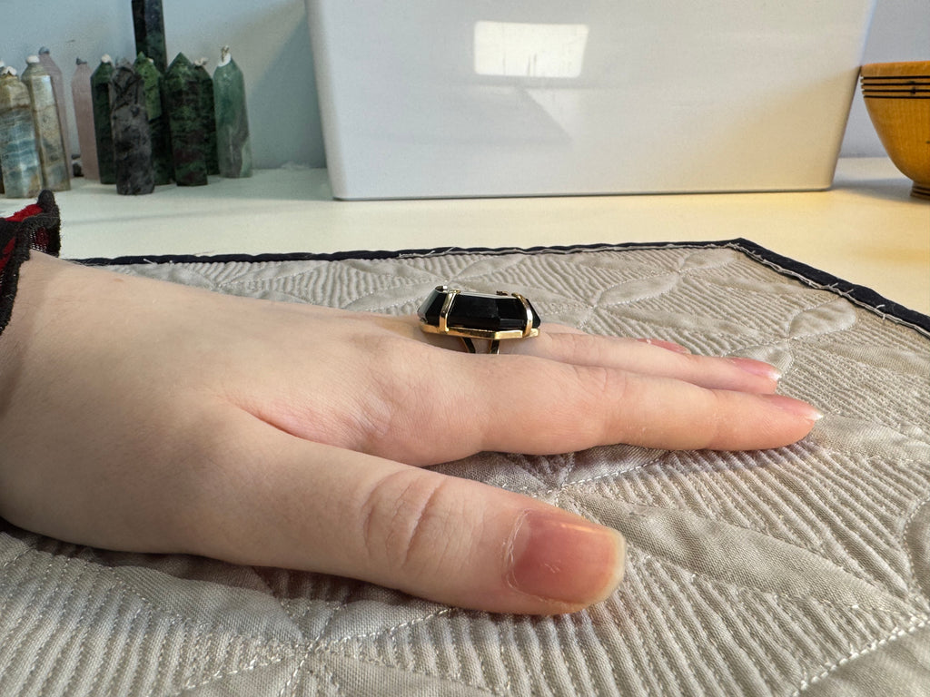 Hand wearing a ring on a textured surface with a blurred background