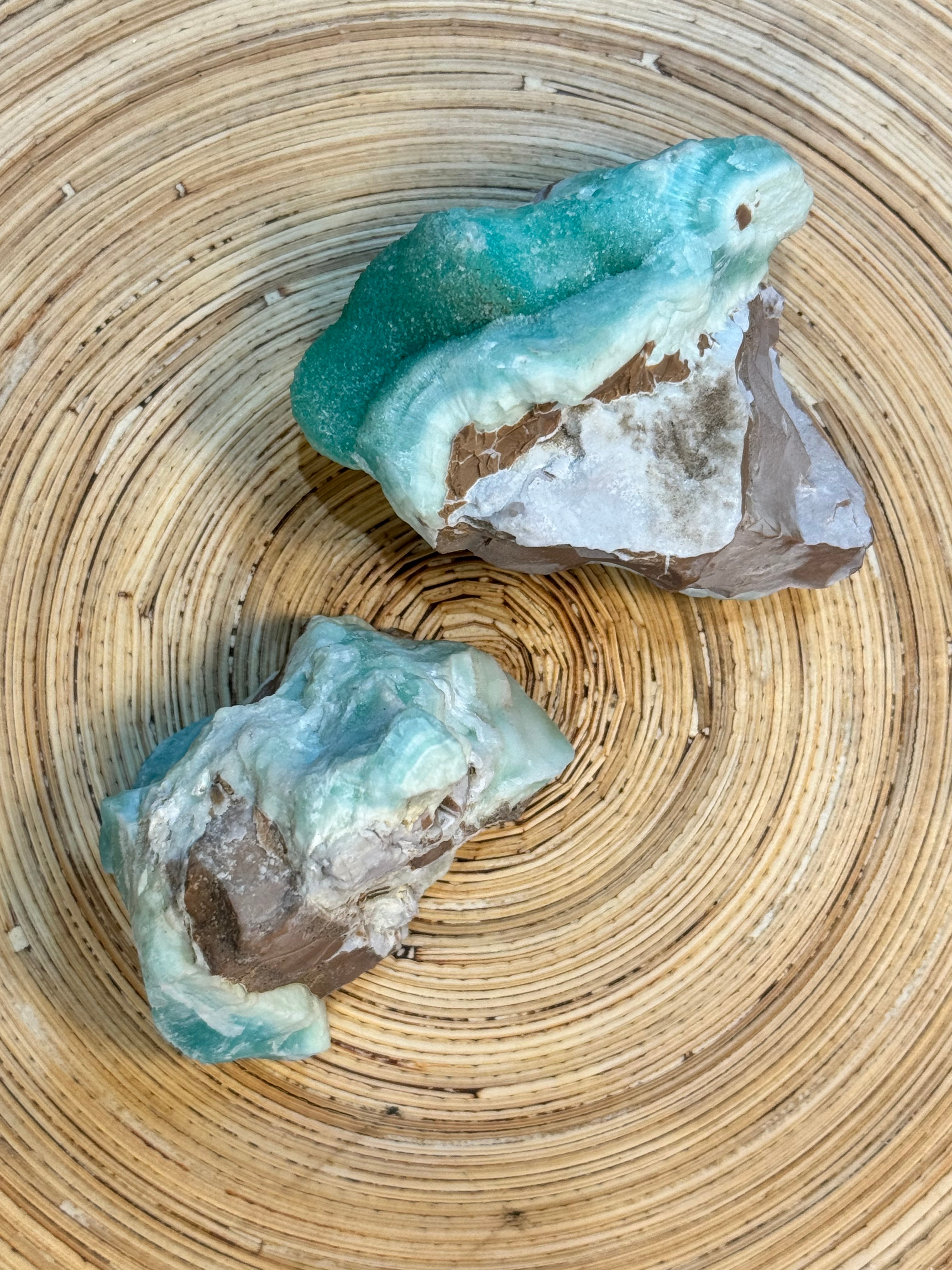 Two turquoise-colored rocks on a woven surface