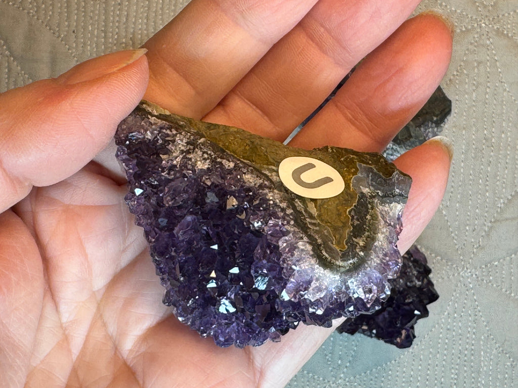 Amethyst crystal held in a hand with a blurred background