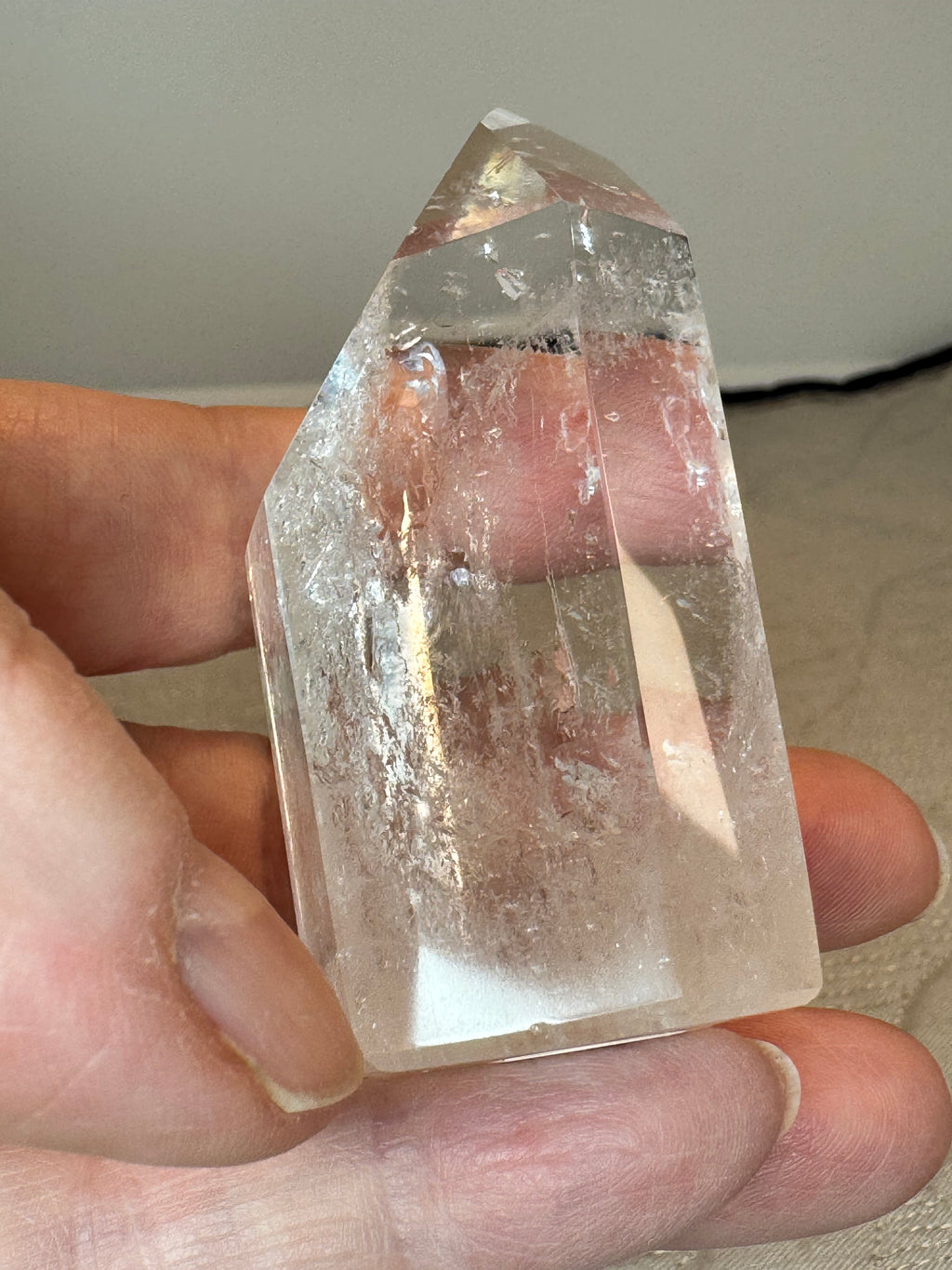 Clear crystal held in a hand against a neutral background