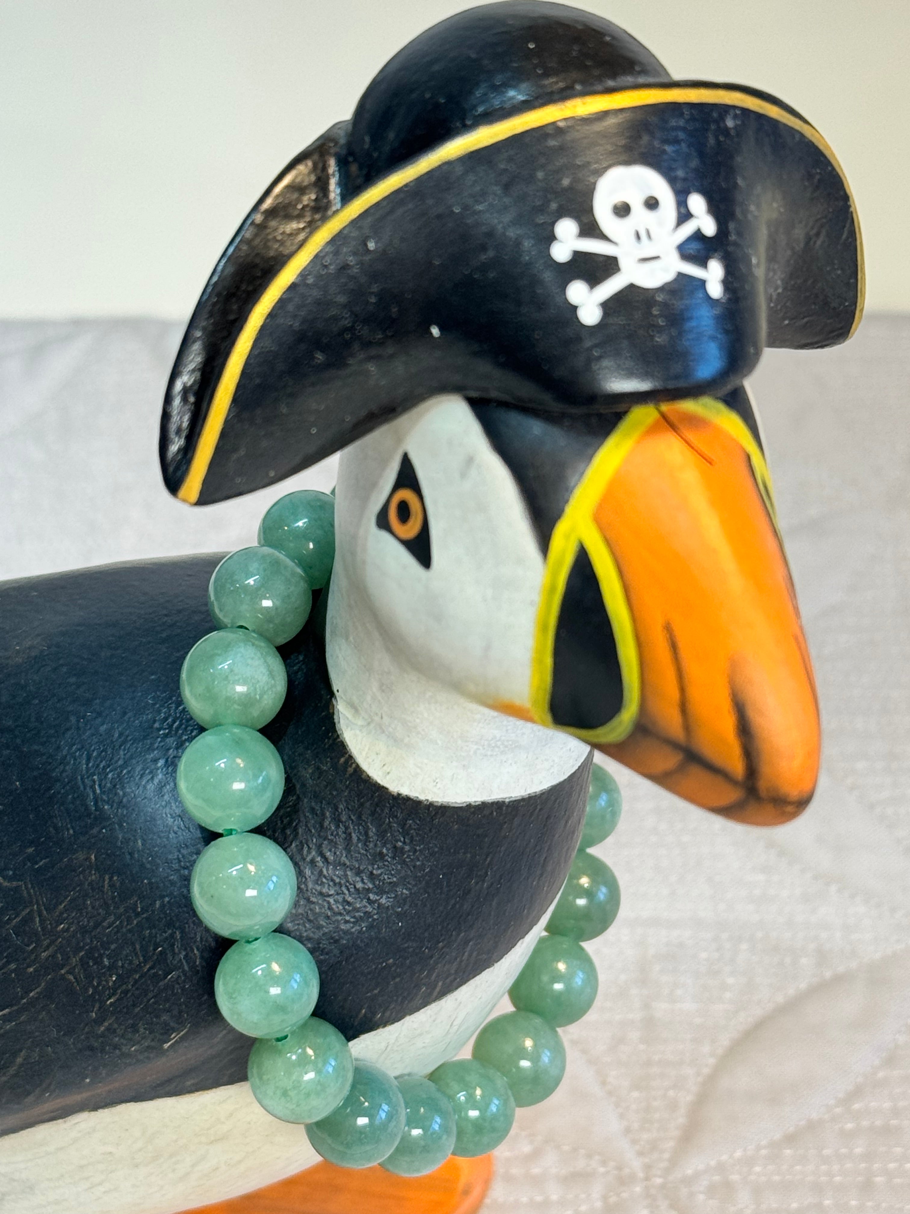 Puffin wearing a pirate hat with a skull and crossbones, wearing a green jadeite beaded bracelet.