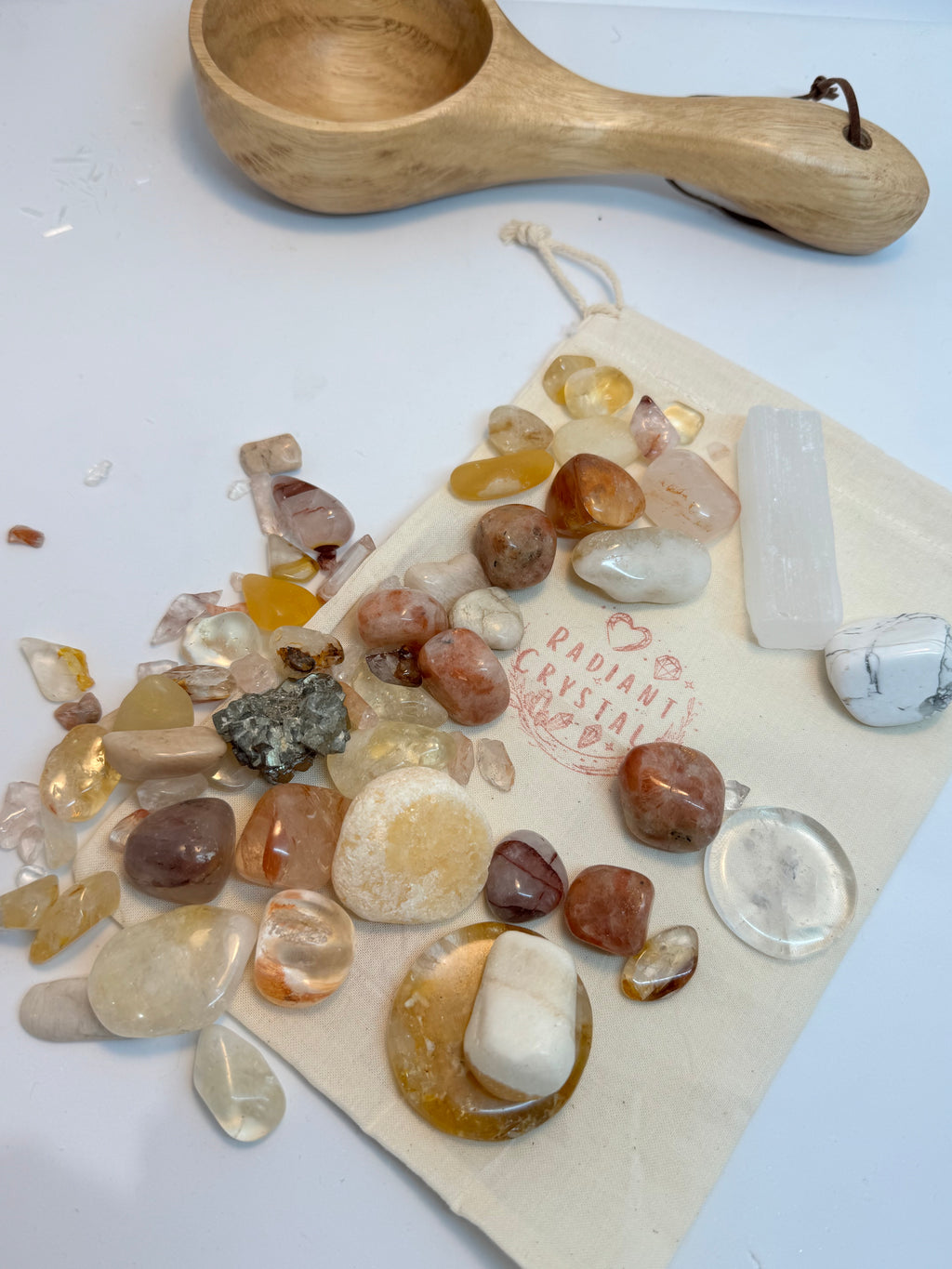 Collection of stones and a wooden scoop on a white surface