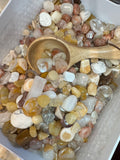 Assorted small stones with a wooden spoon in a white container
