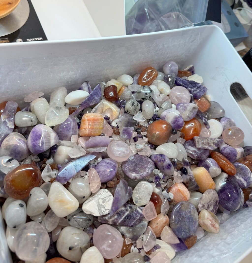 Assorted colored gemstones in a white container on a table.