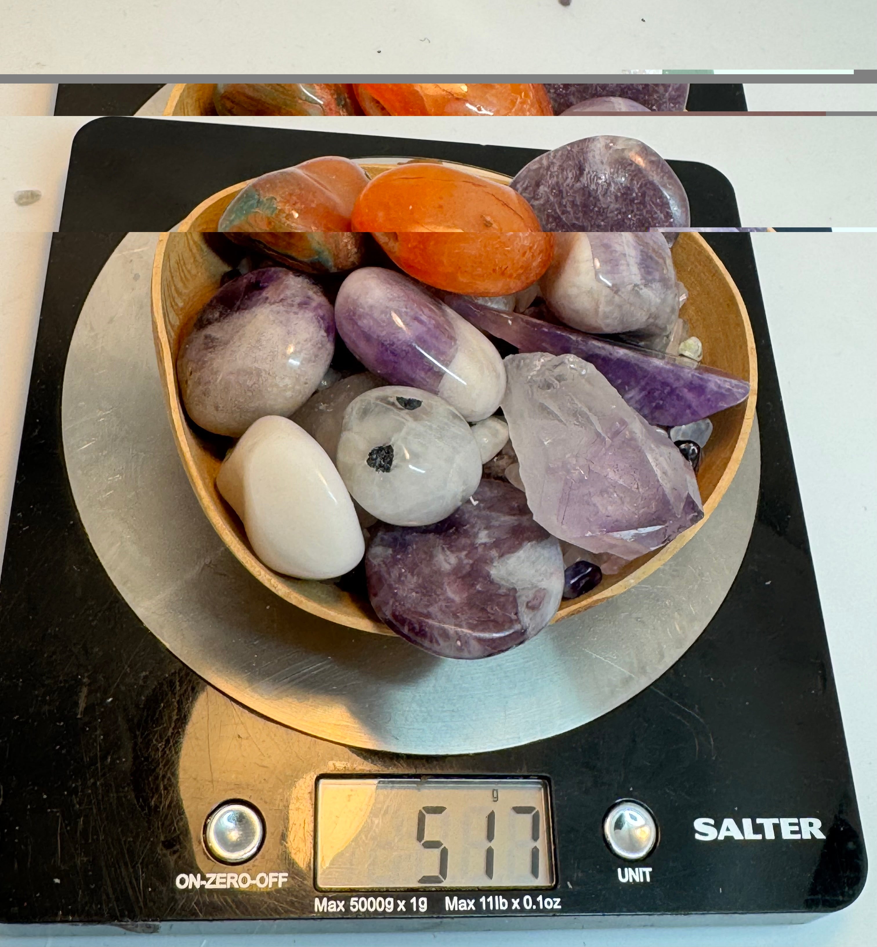 Bowl of multicolored stones on a Salter scale displaying a weight.
