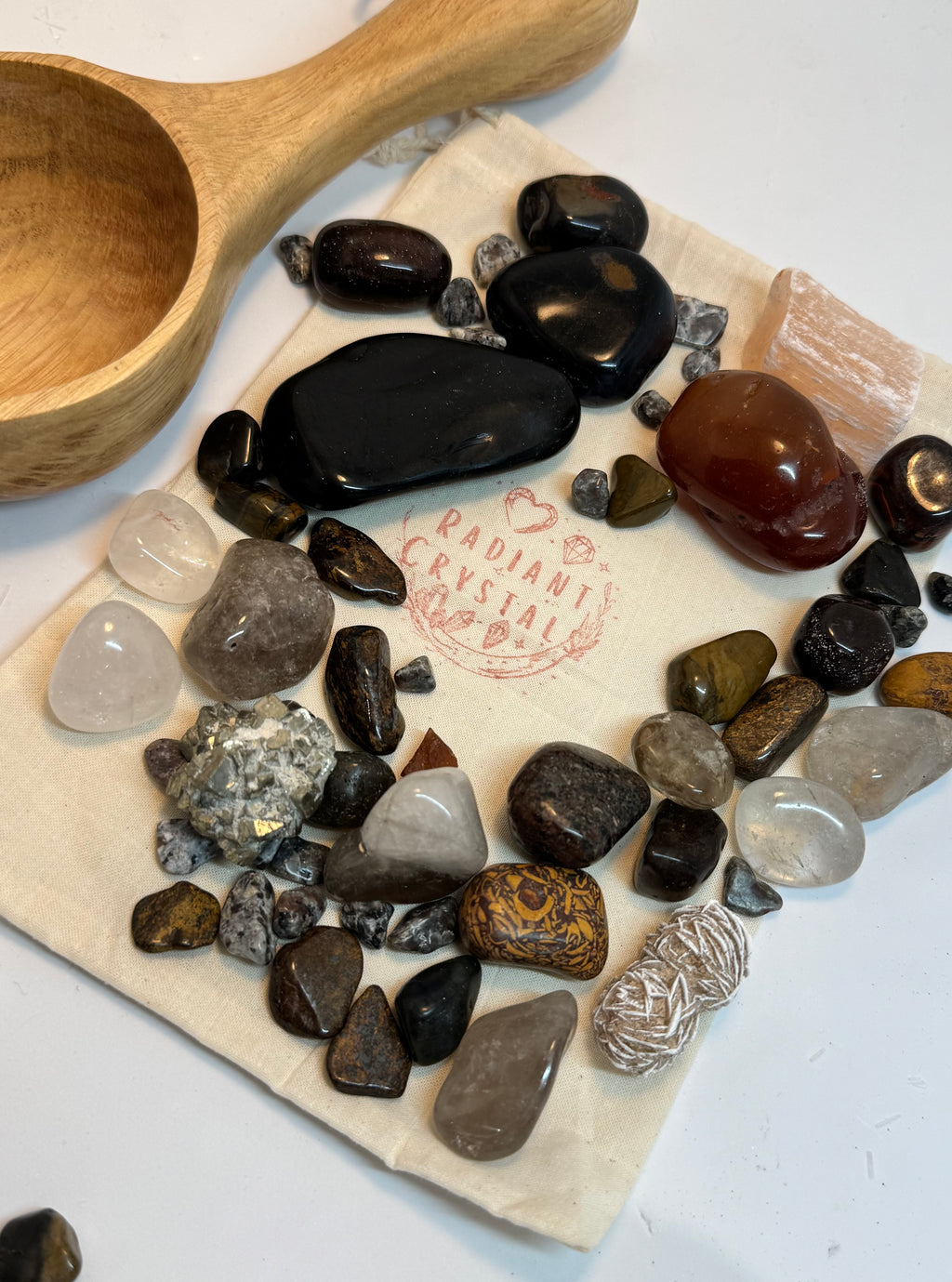 Collection of various stones on a cloth with a wooden scoop, on a light background