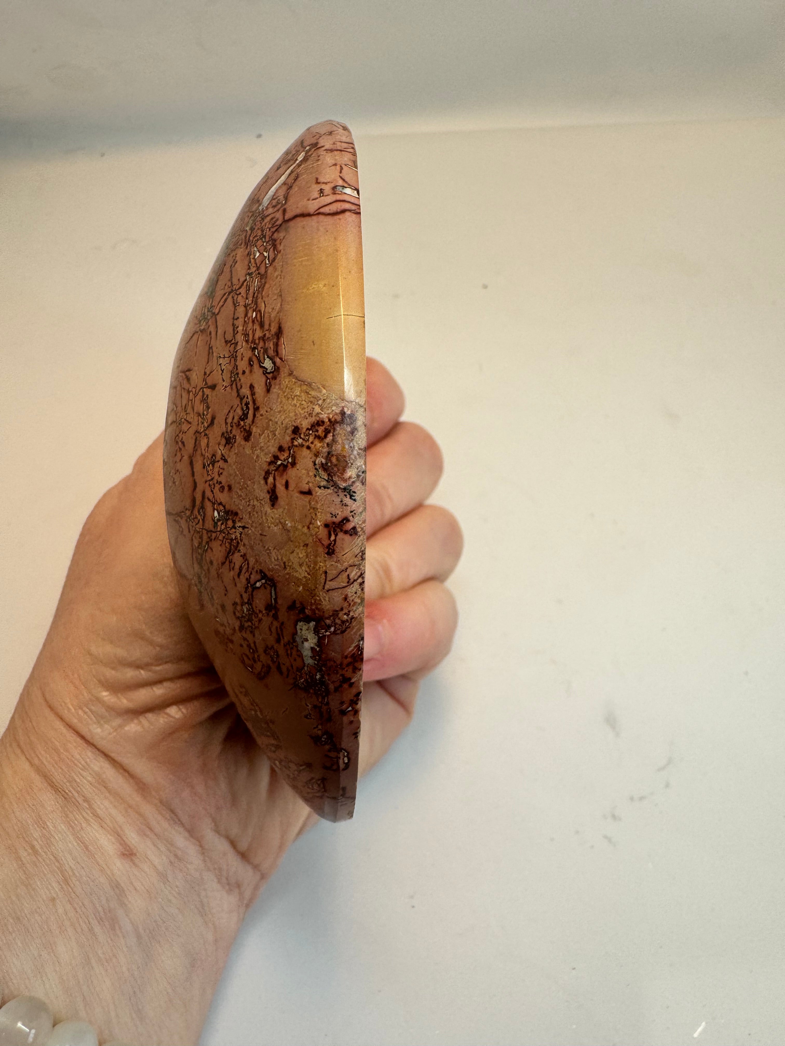 Hand holding a marbled stone bowl against a plain background