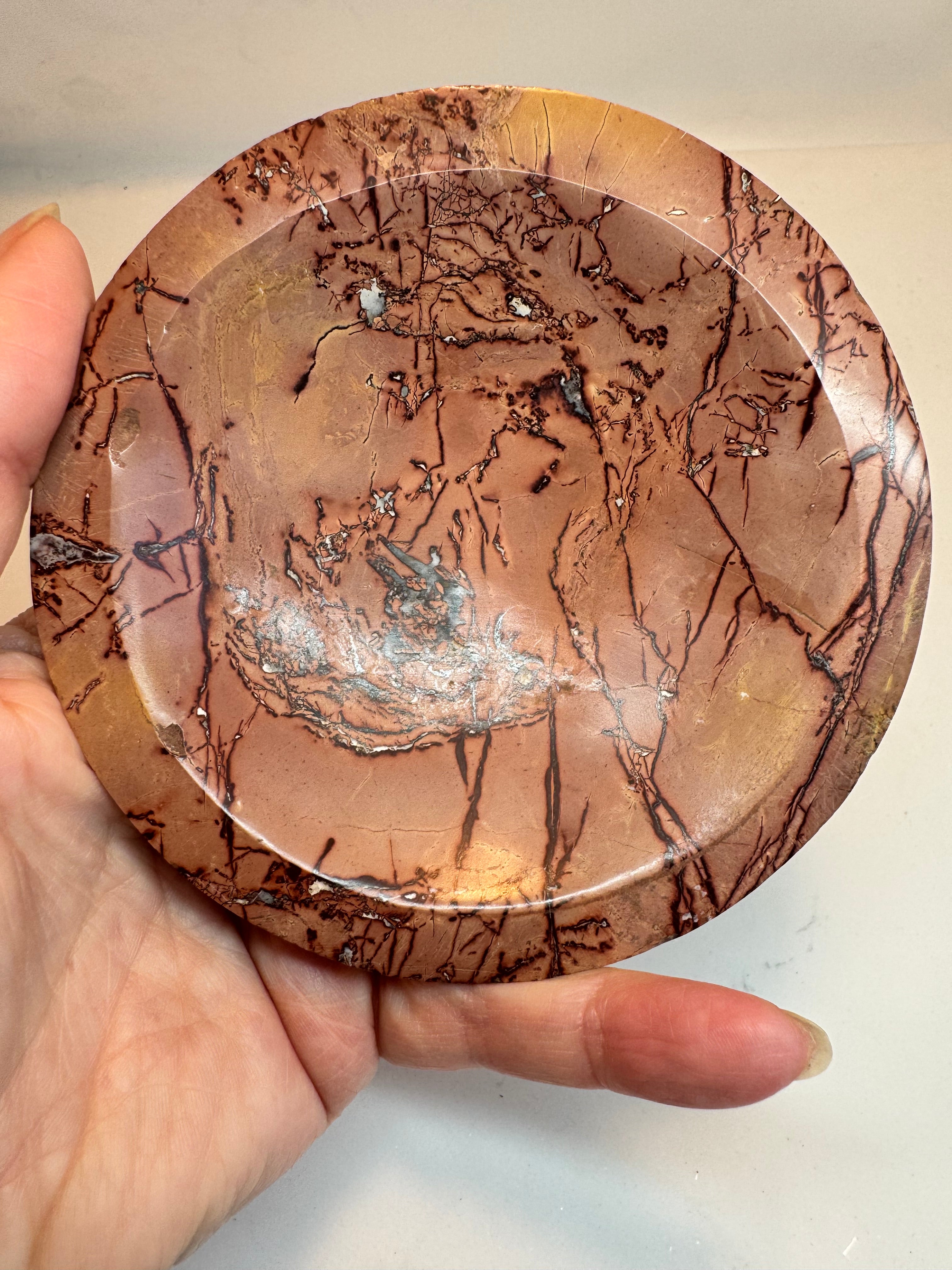 Marble-patterned stone held by a hand against a neutral background