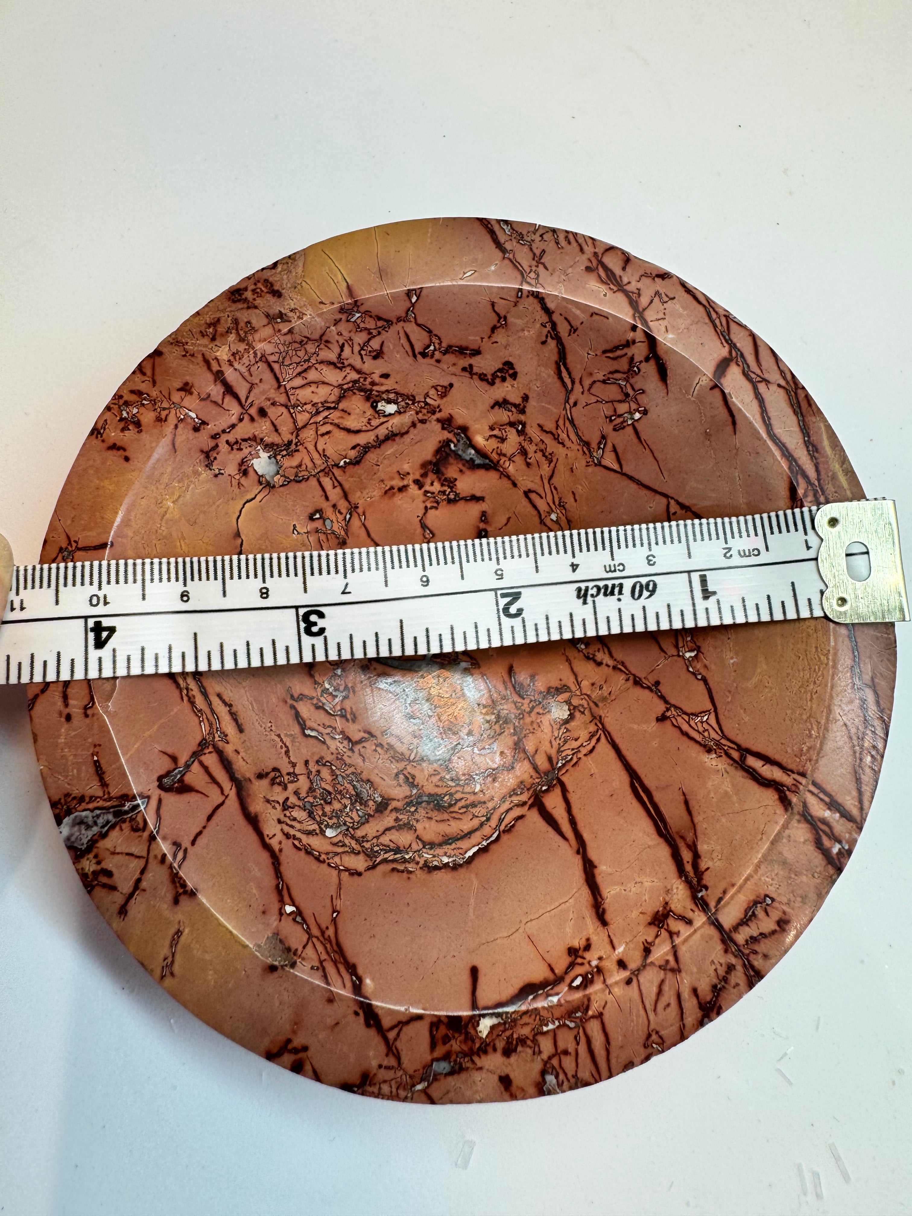 Round brown stone with a ruler for scale on a white background