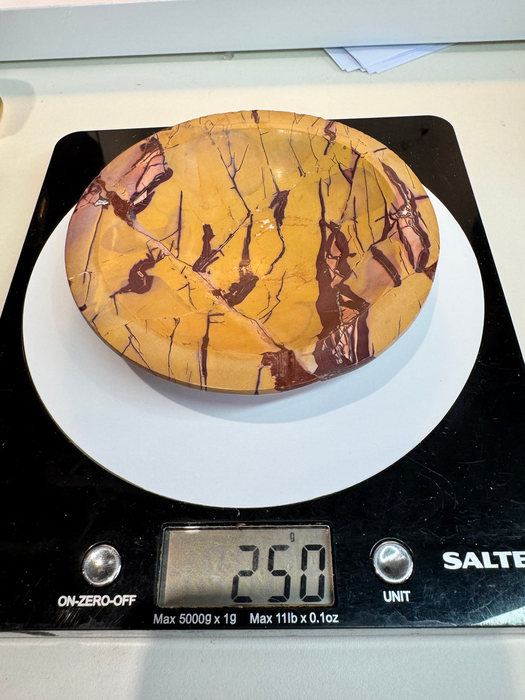 Decorative plate with a natural pattern on a digital kitchen scale displaying 250 grams.
