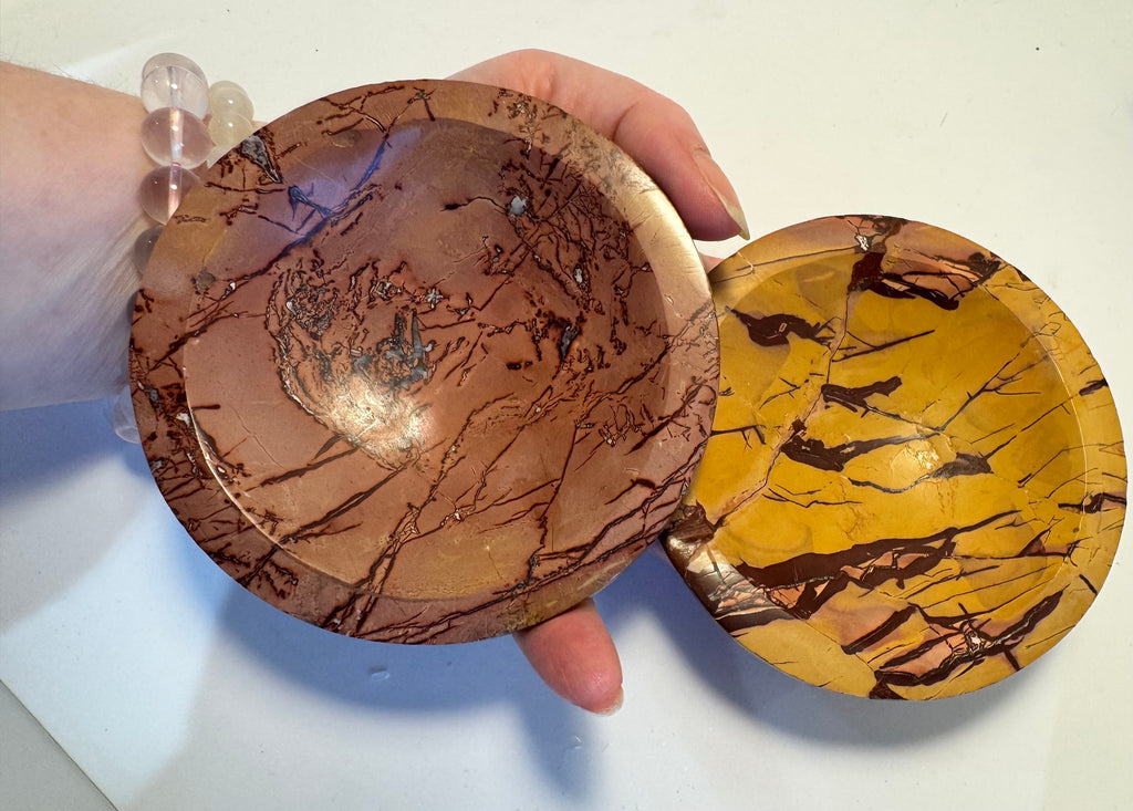 Two marbled mineral bowls held by a hand on a white background