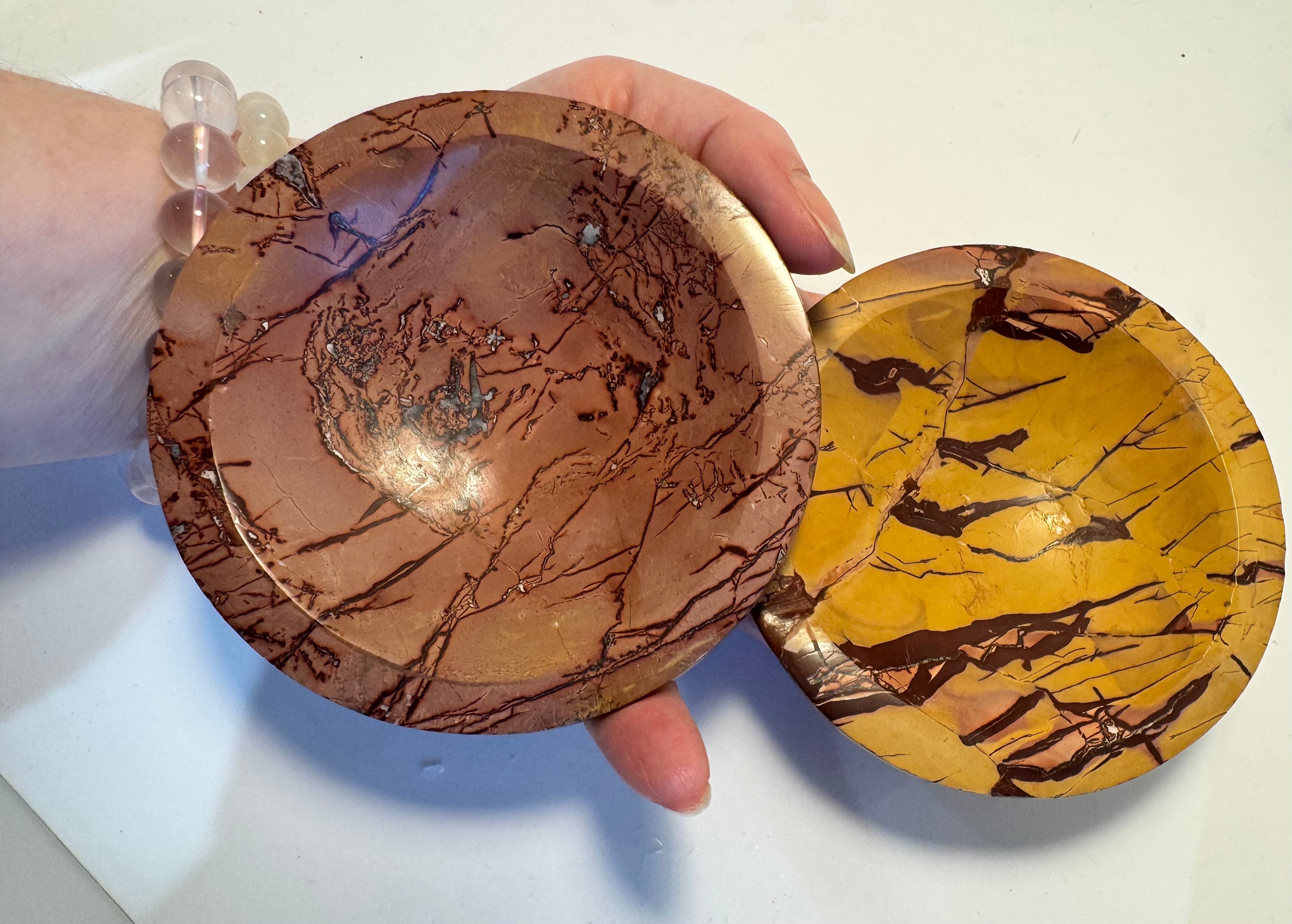 Two marbled mineral bowls held by a hand on a white background