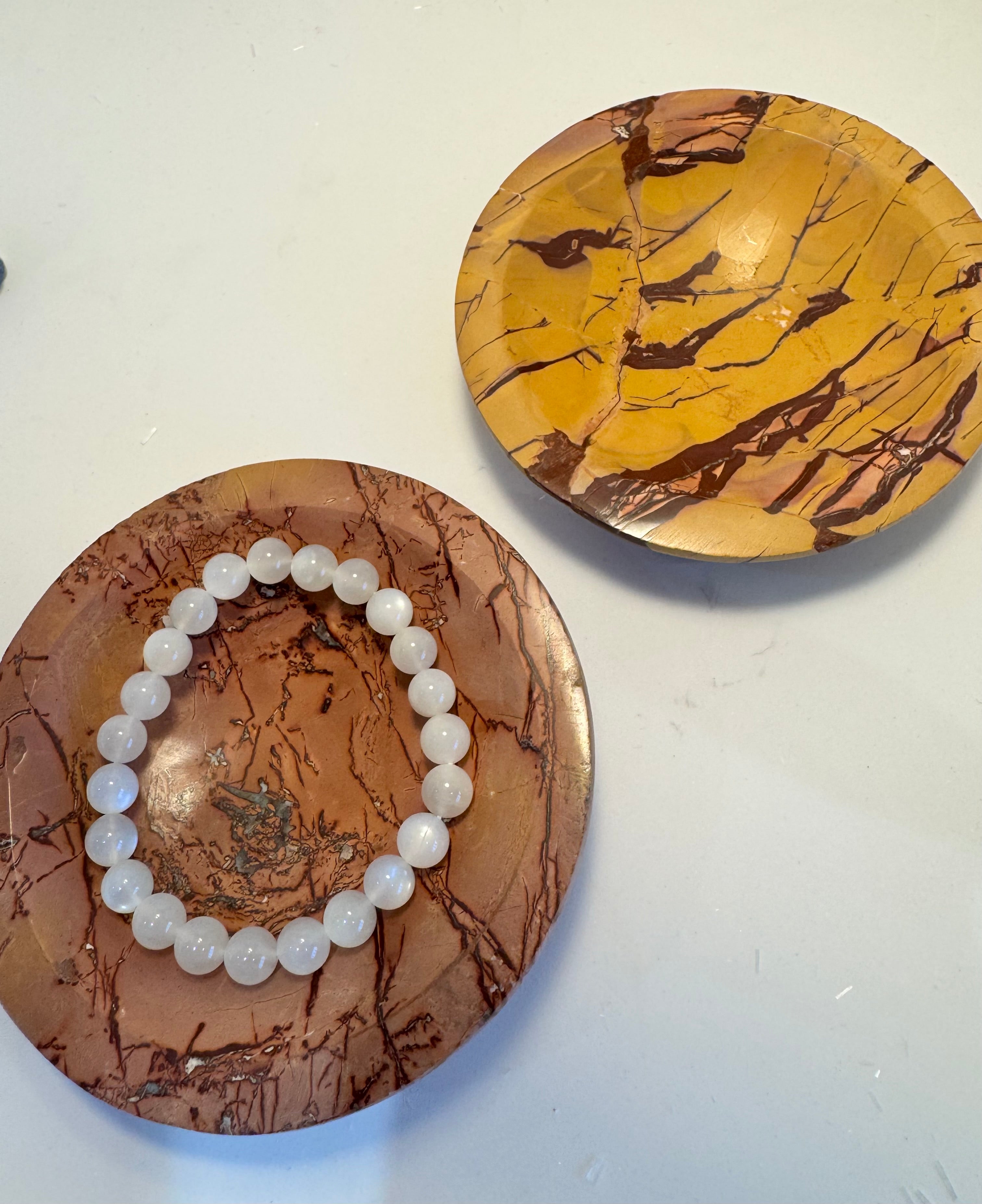 Two marbled bowls with a bracelet on one of them against a white background