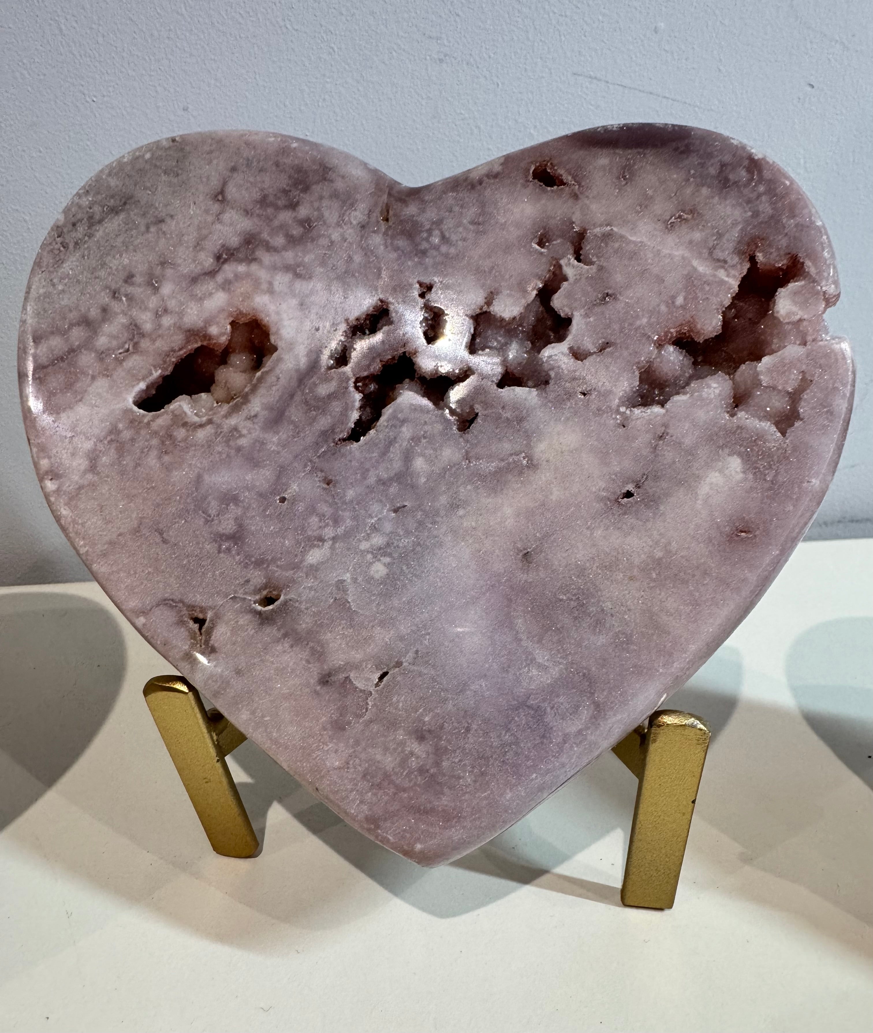 Heart-shaped purple stone on a stand against a light gray background