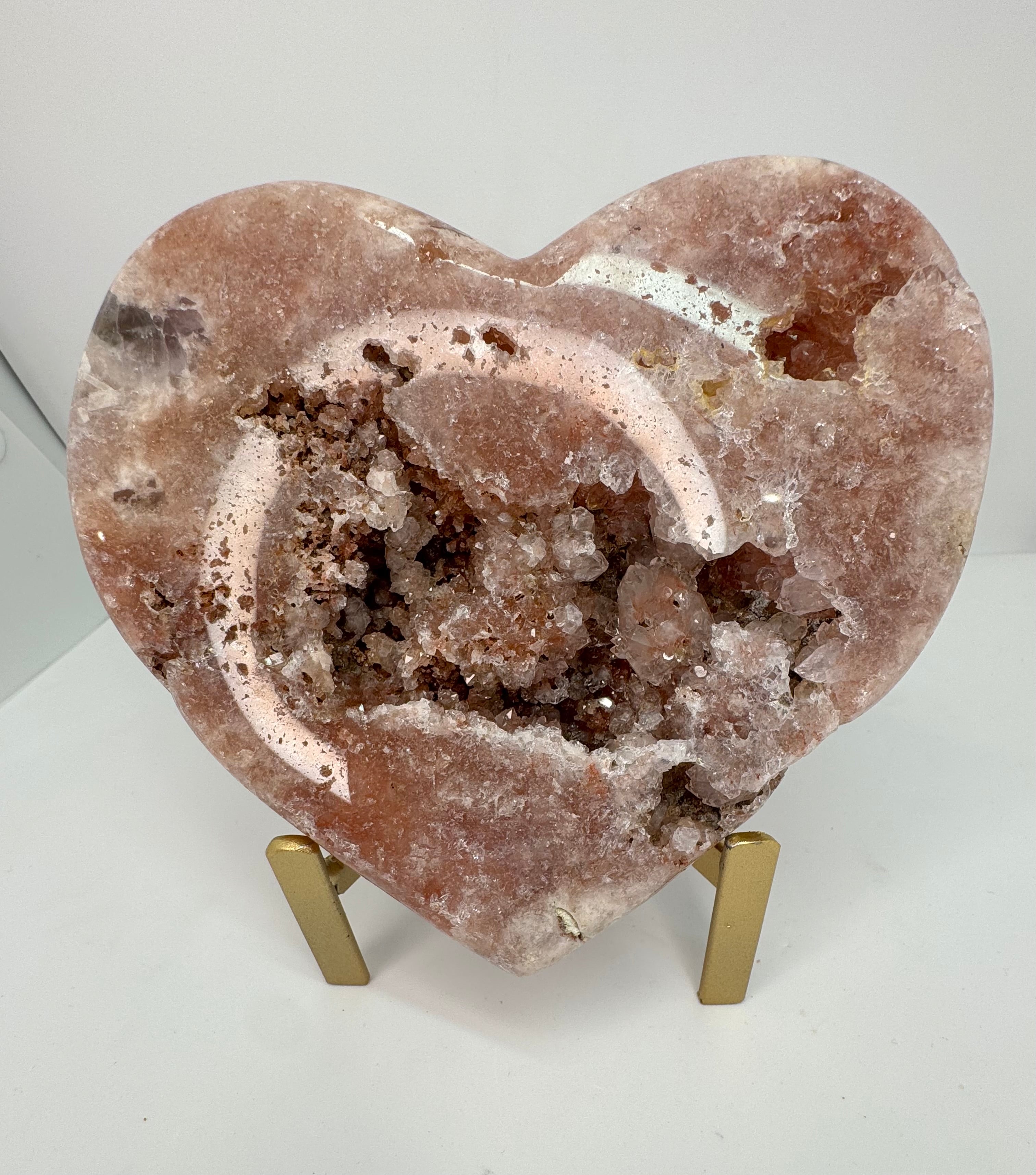 Heart-shaped crystal rock on a stand with a white background