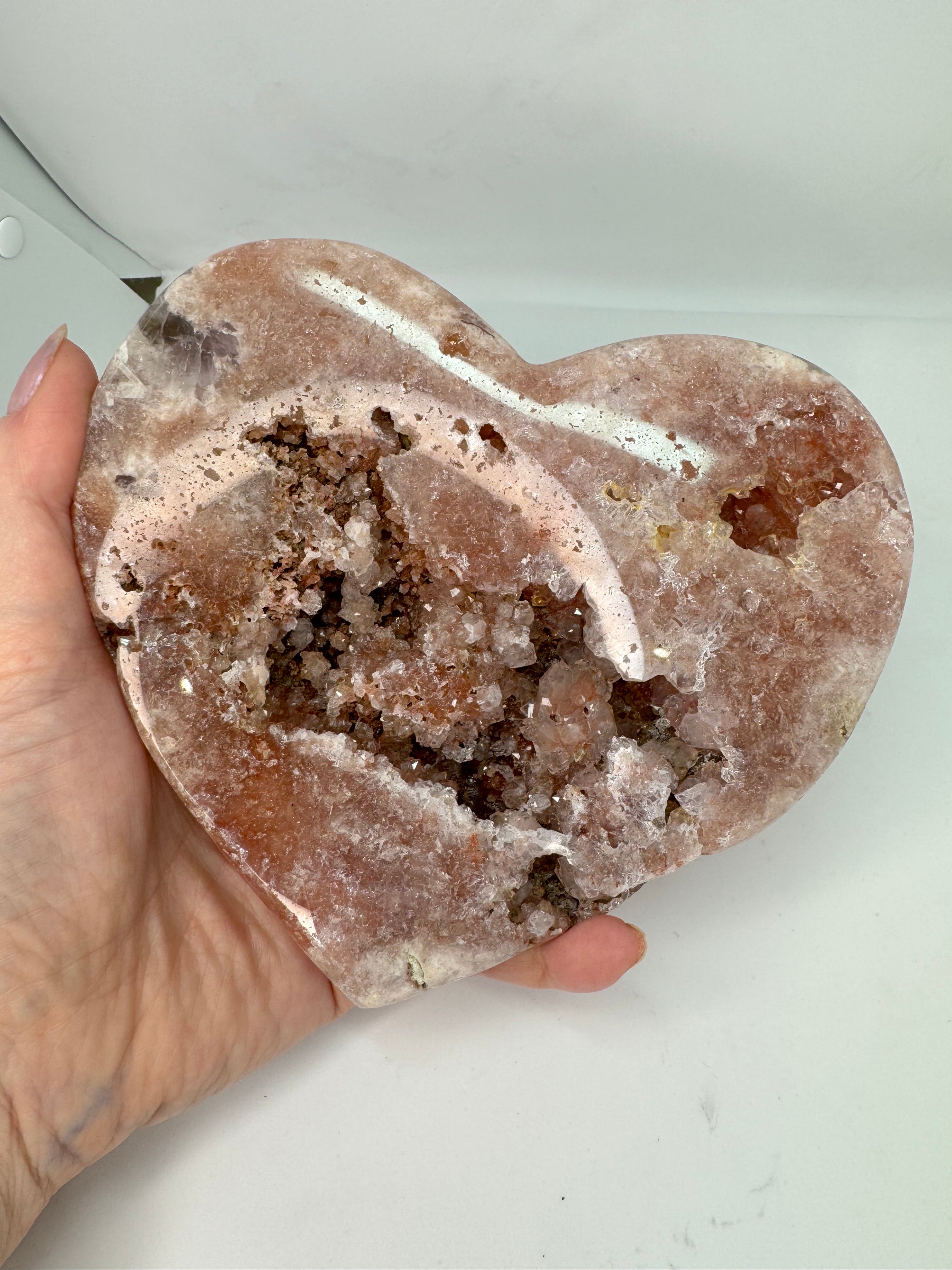 Hand holding a large crystal rock with intricate formations against a white background