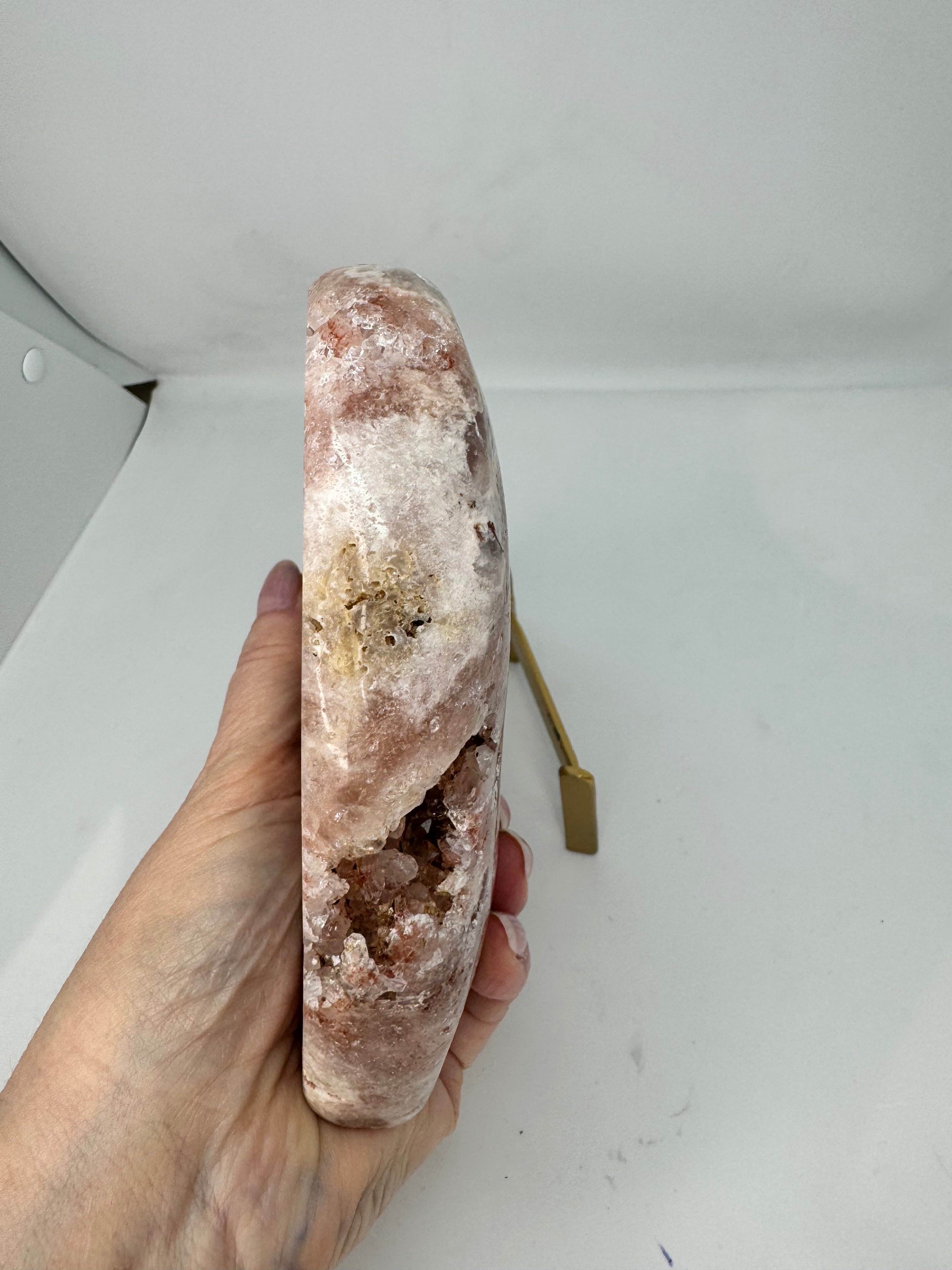 Hand holding a large crystal side view against a plain background