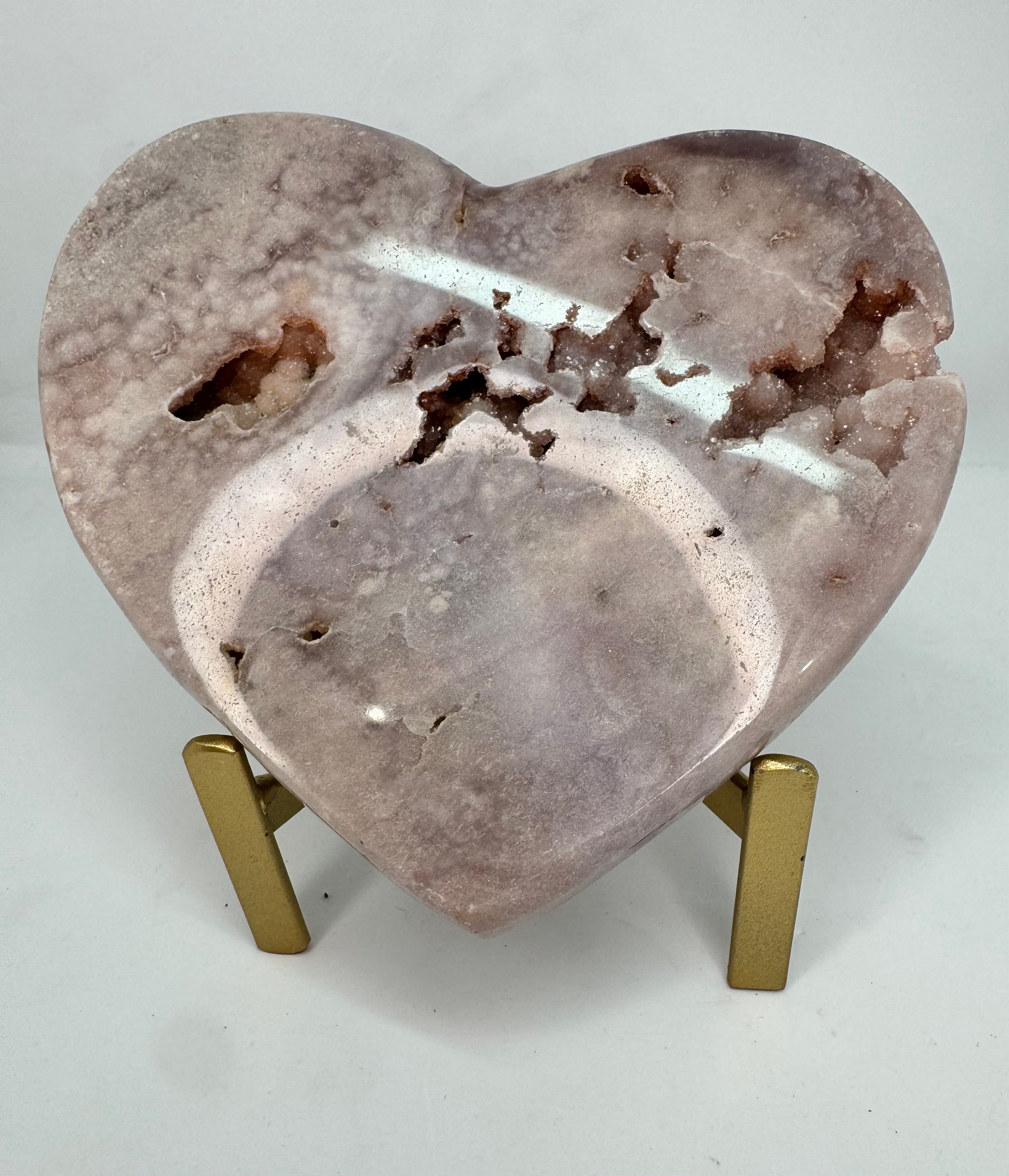 Heart-shaped stone on a small brass stand against a white background