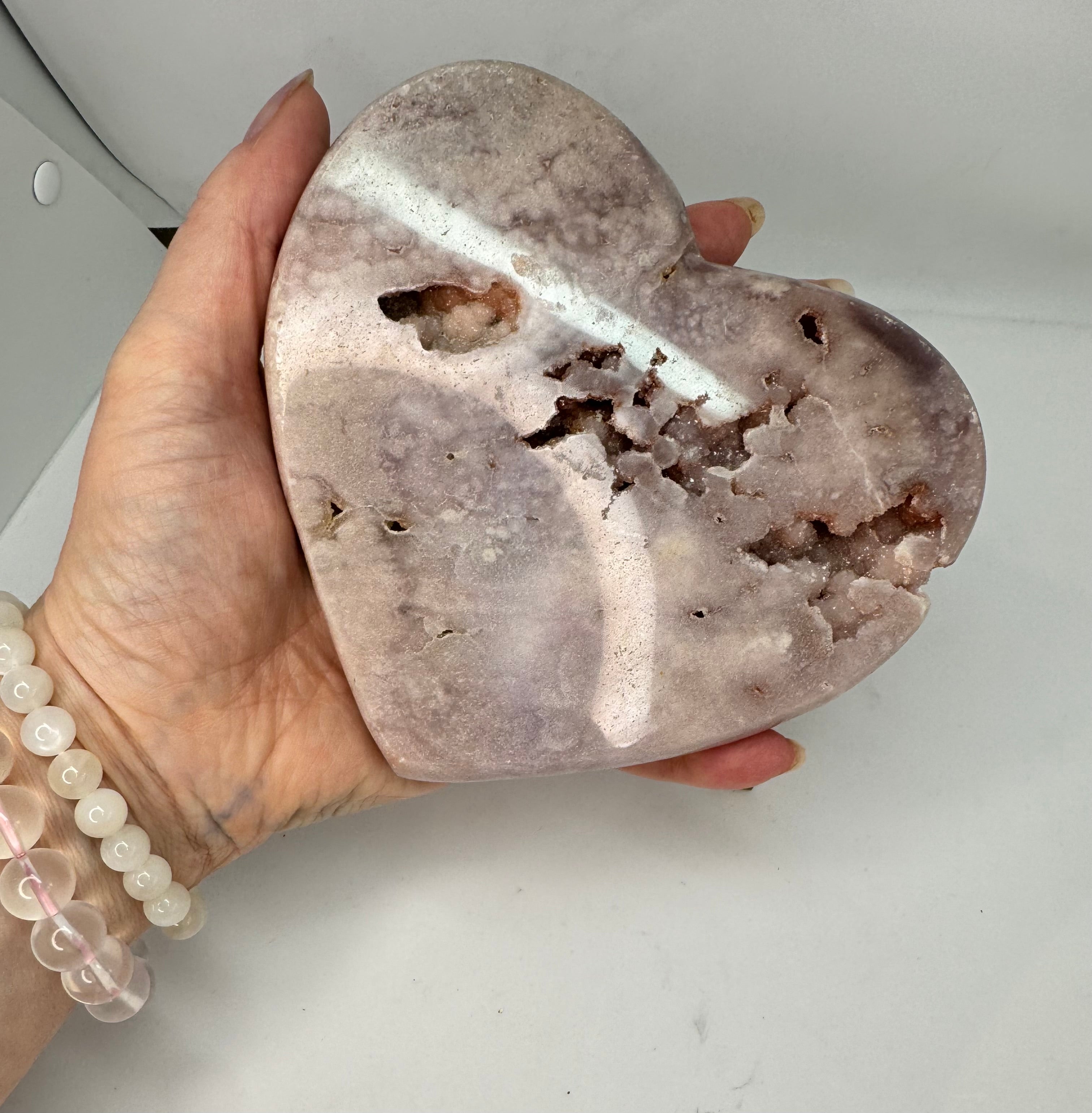Heart-shaped stone held in a hand against a neutral background
