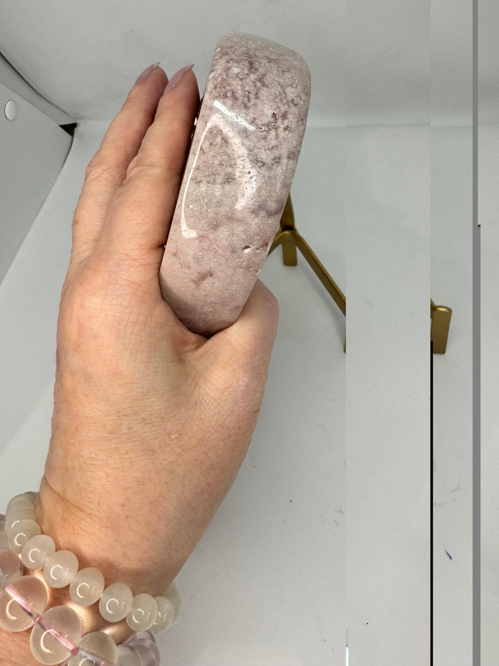 Hand holding a pink stone, side view with a blurred background
