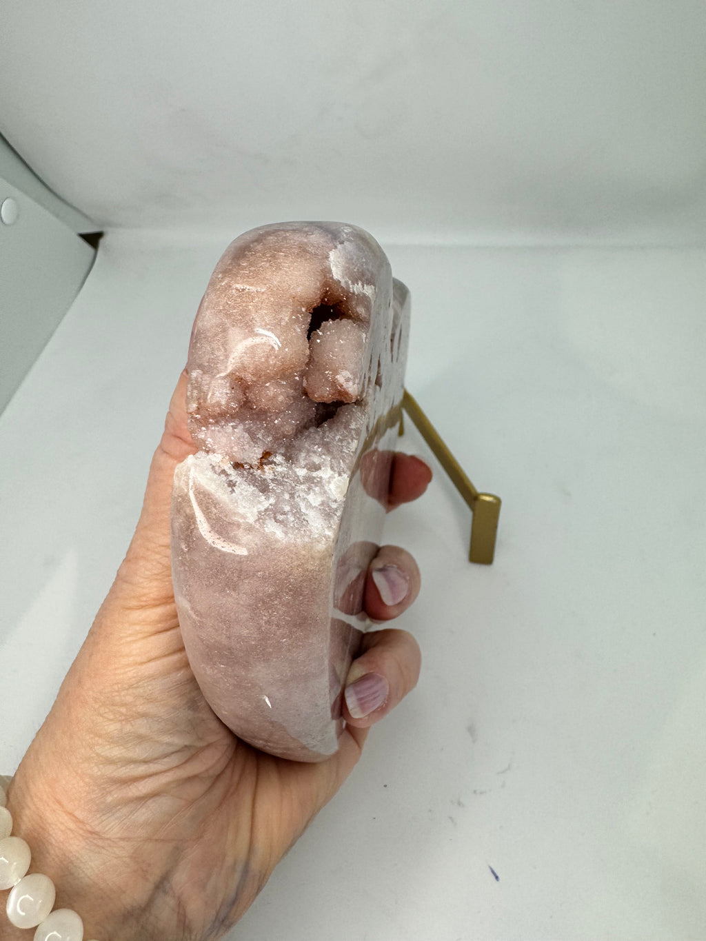 Hand holding a large crystal or stone with a white background