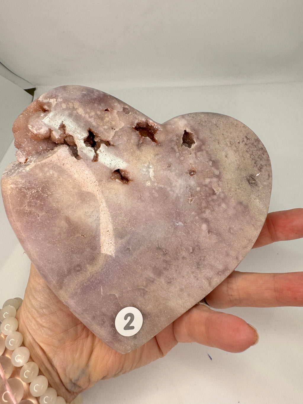 Heart-shaped stone held by a hand against a neutral background