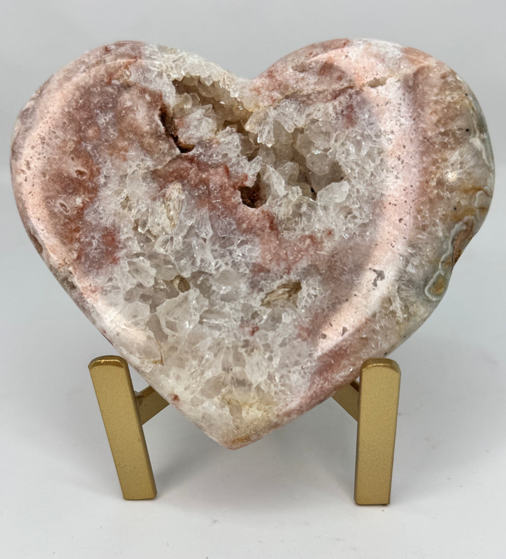 Heart-shaped crystal rock on a stand against a white background