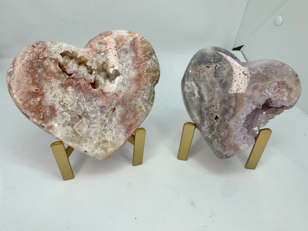 Two heart-shaped geode crystals on stands against a white background
