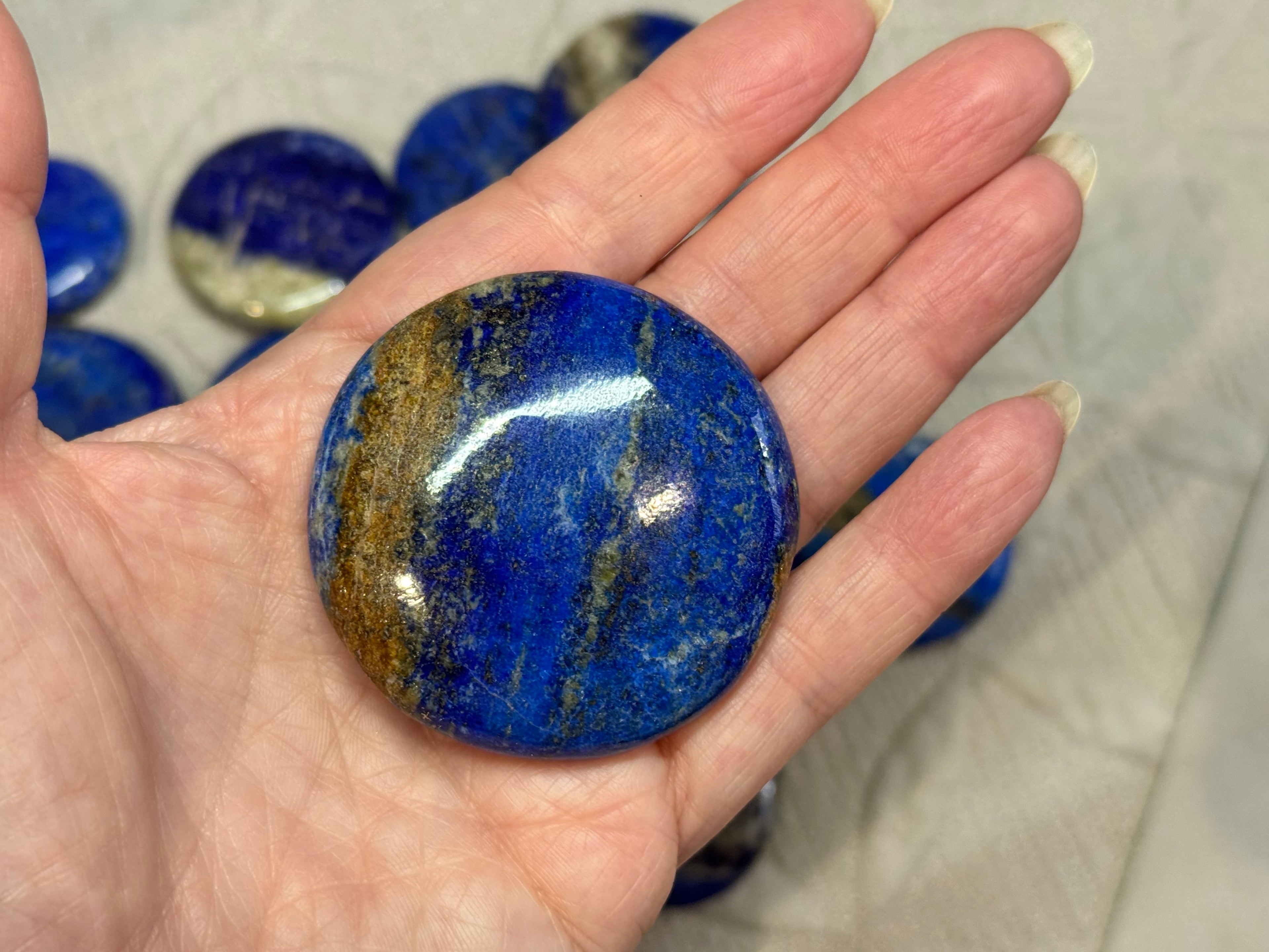 Hand holding a blue stone with other stones in the background