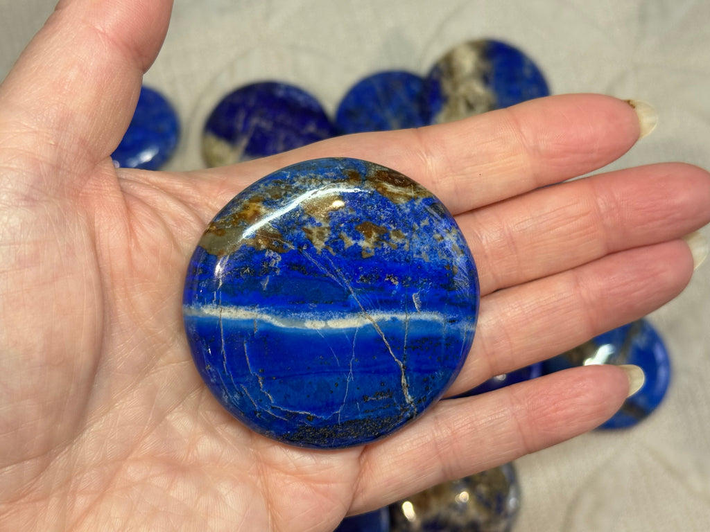 Hand holding a blue stone with other stones in the background