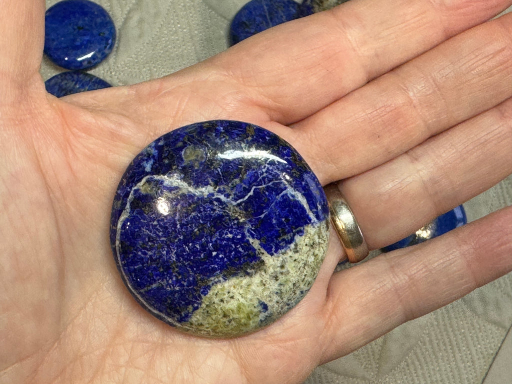 Hand holding a blue and green marbled stone with a blurred background