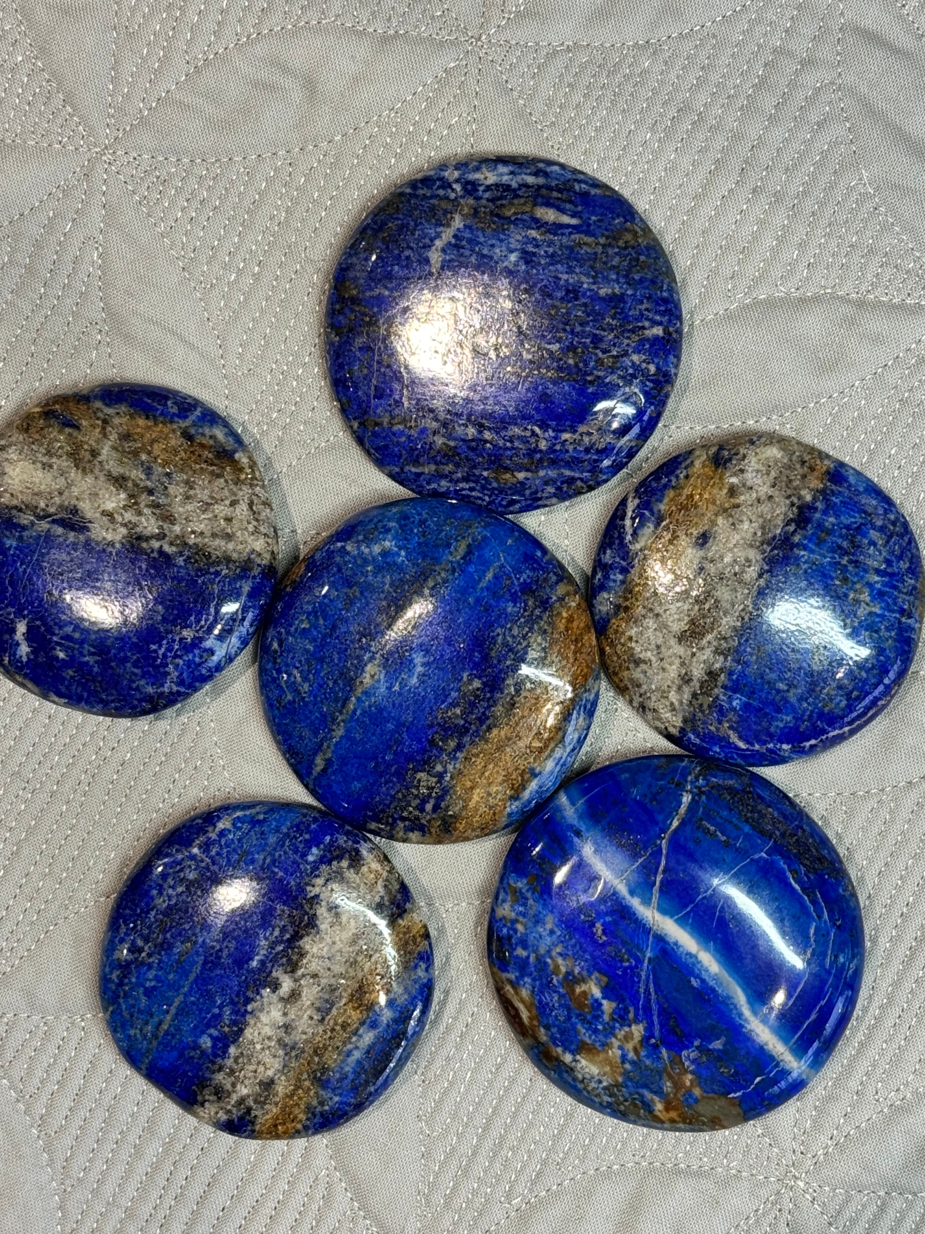 Seven blue stones with brown streaks on a textured white surface