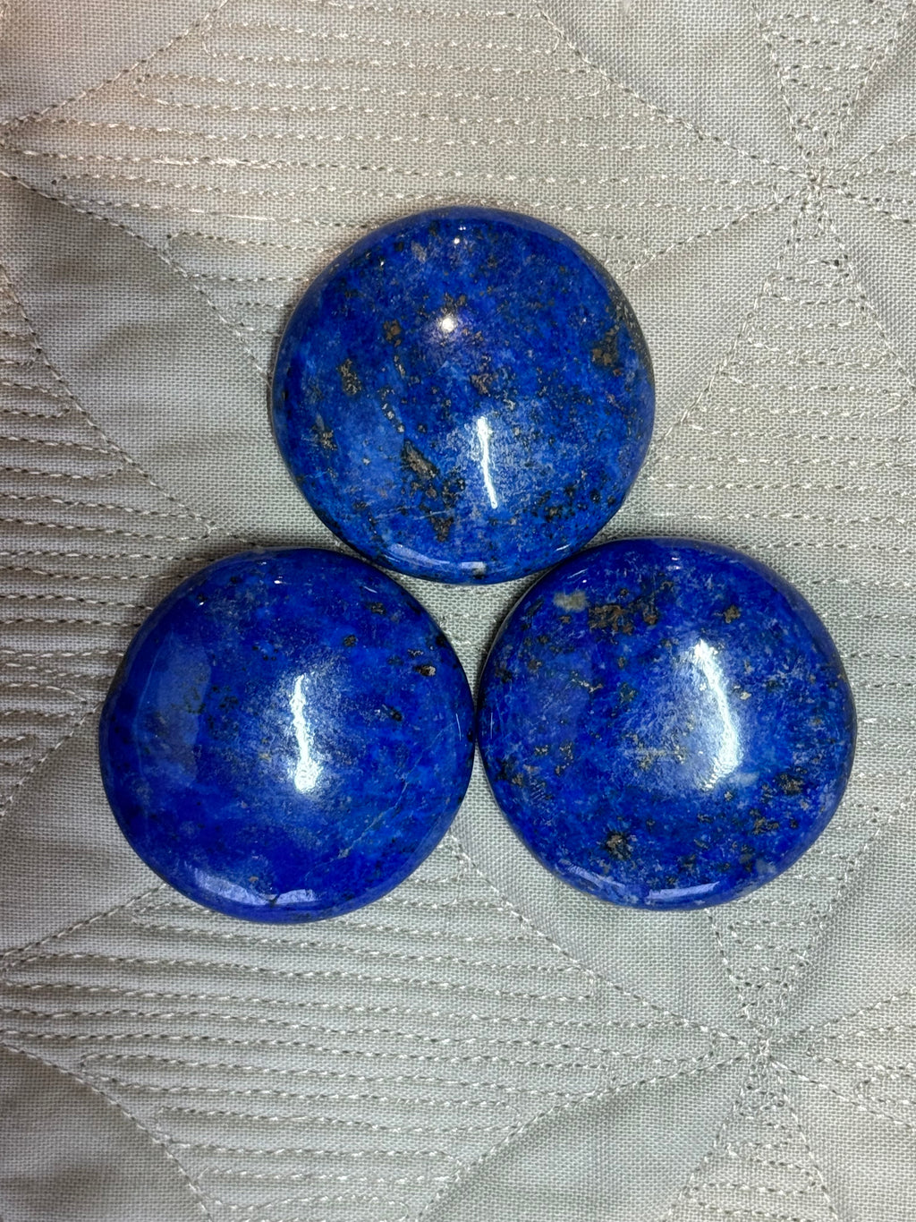 Three blue stones on a textured white fabric background