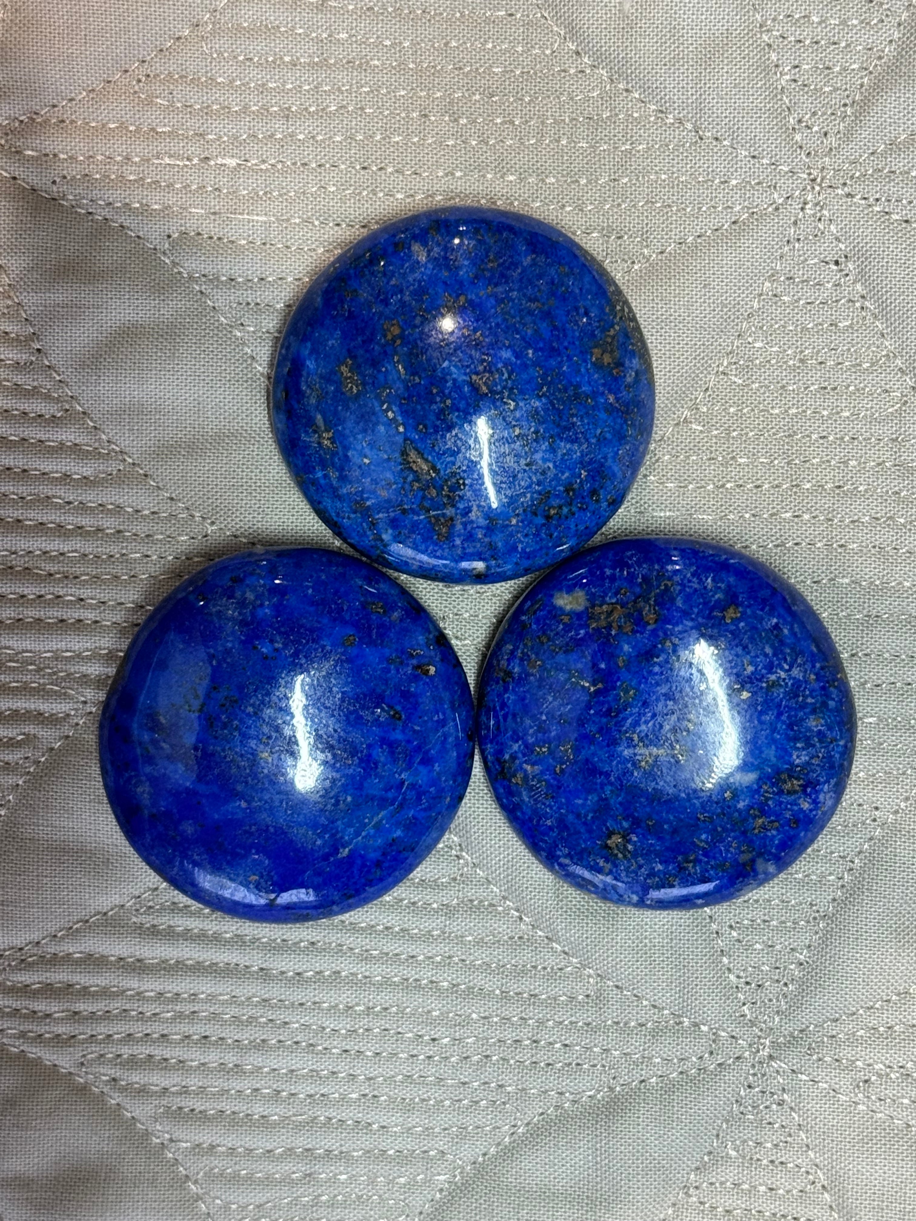 Three blue stones on a textured white fabric background