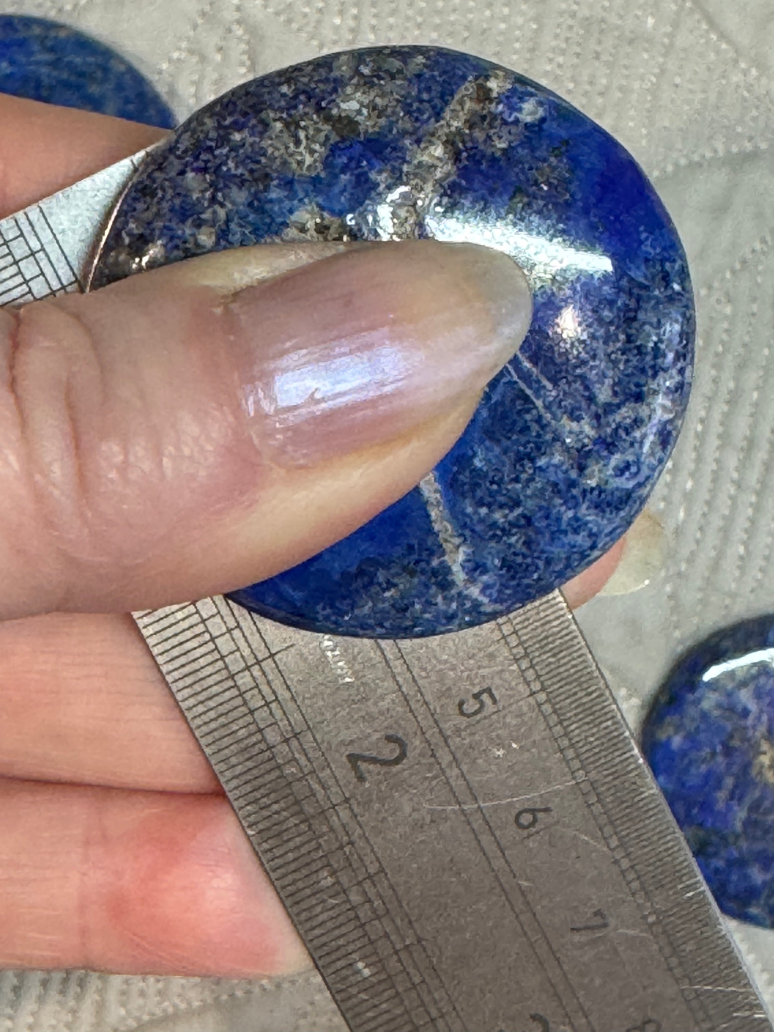 Lapis lazuli stone being measured with a ruler