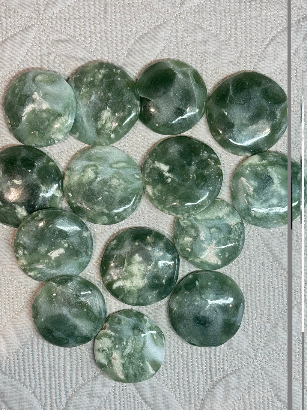 Green stone rounds on a textured white surface