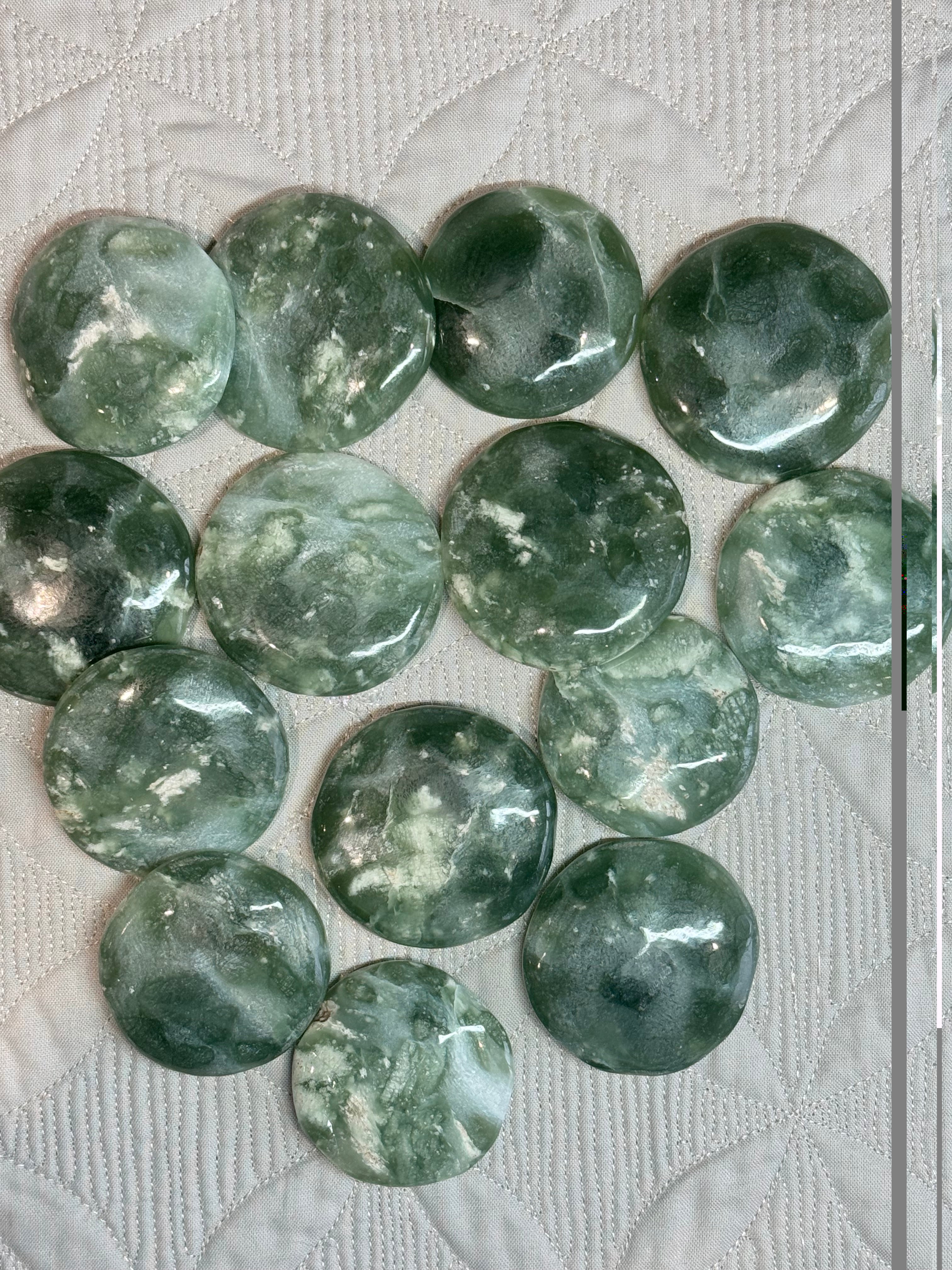 Green stone rounds on a textured white surface