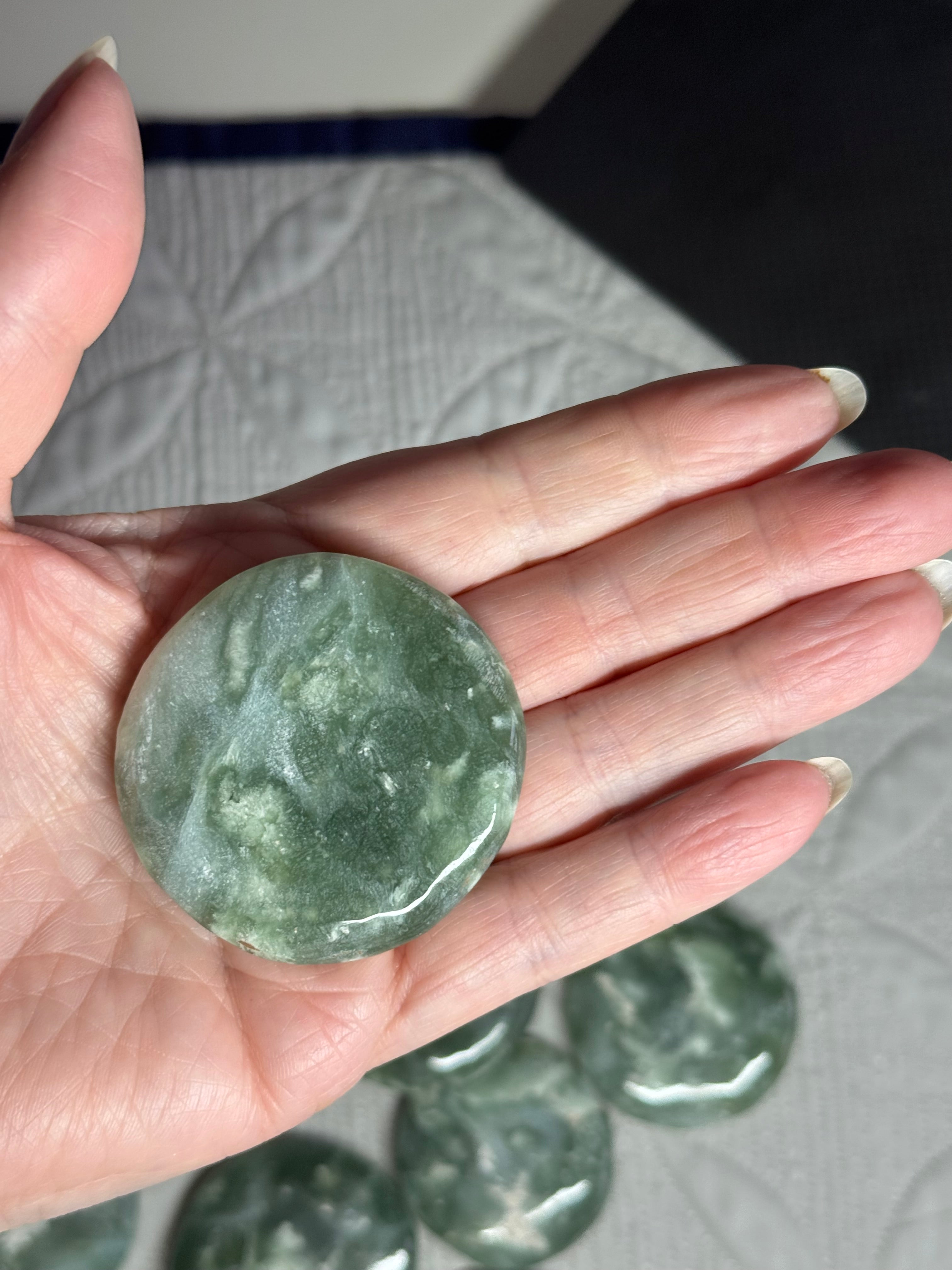 Hand holding a green stone with more stones in the background