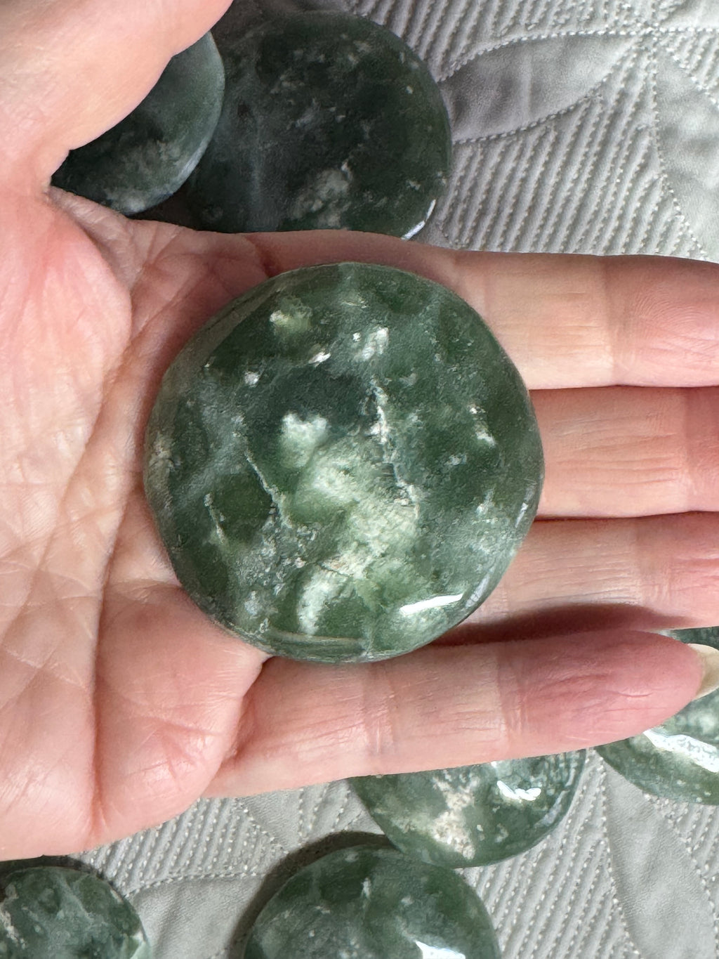 Green stone held in a hand with a textured surface background