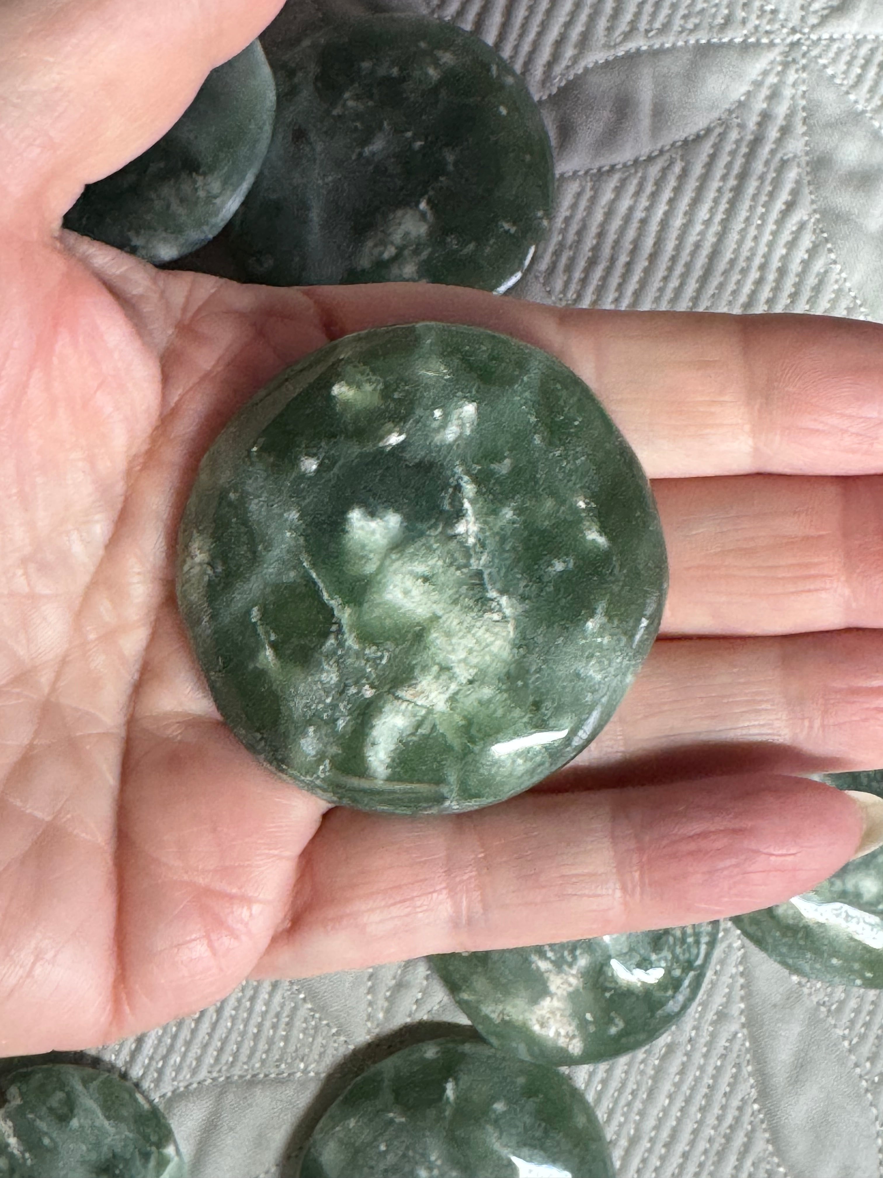 Green stone held in a hand with a textured surface background