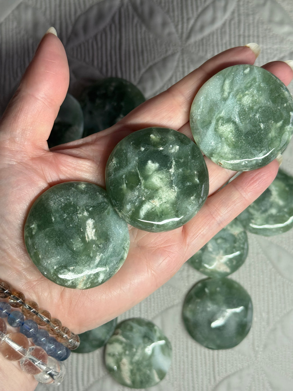 Hand holding green marbled stones with more stones in the background