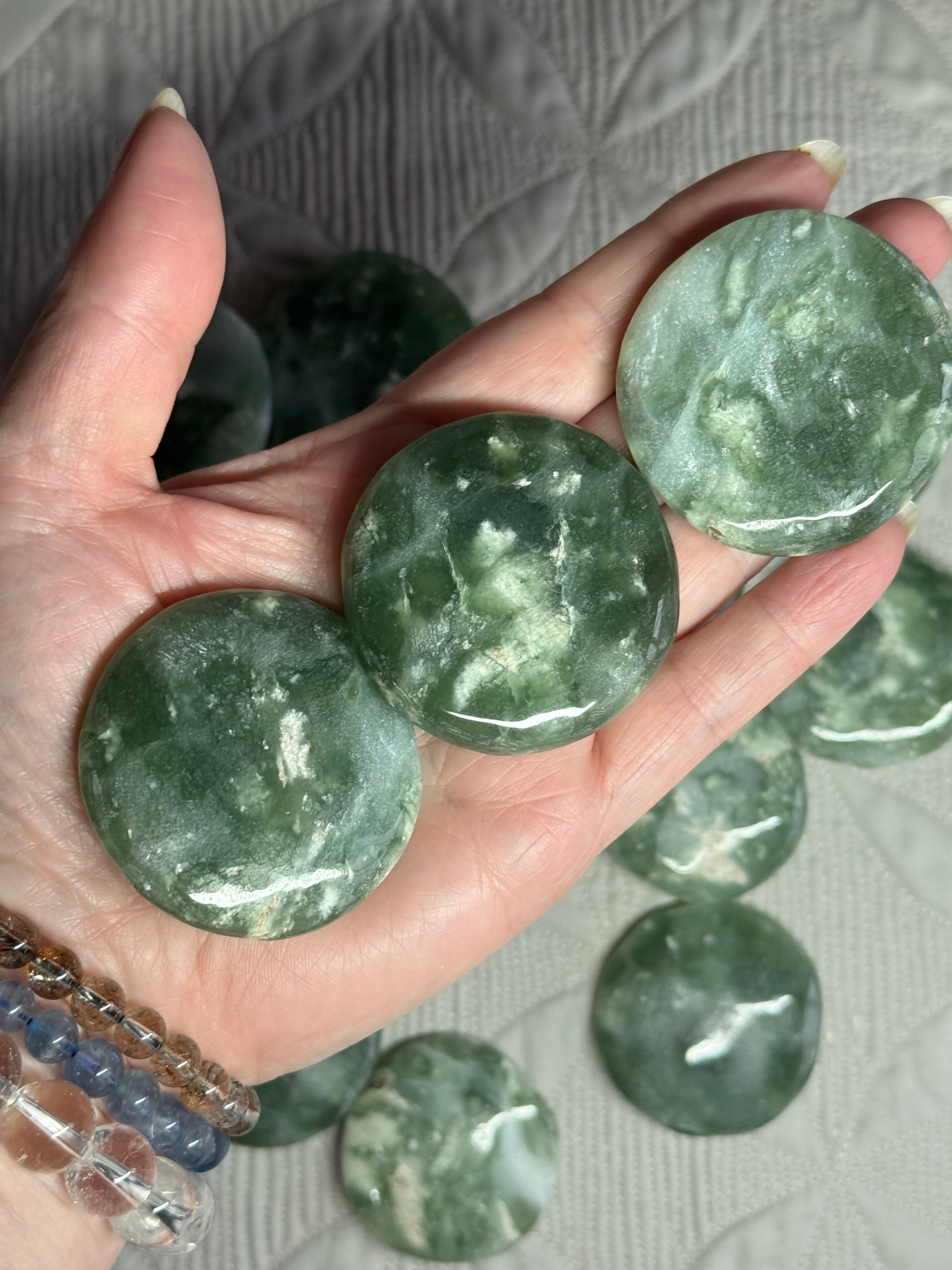 Hand holding green marbled stones with more stones in the background
