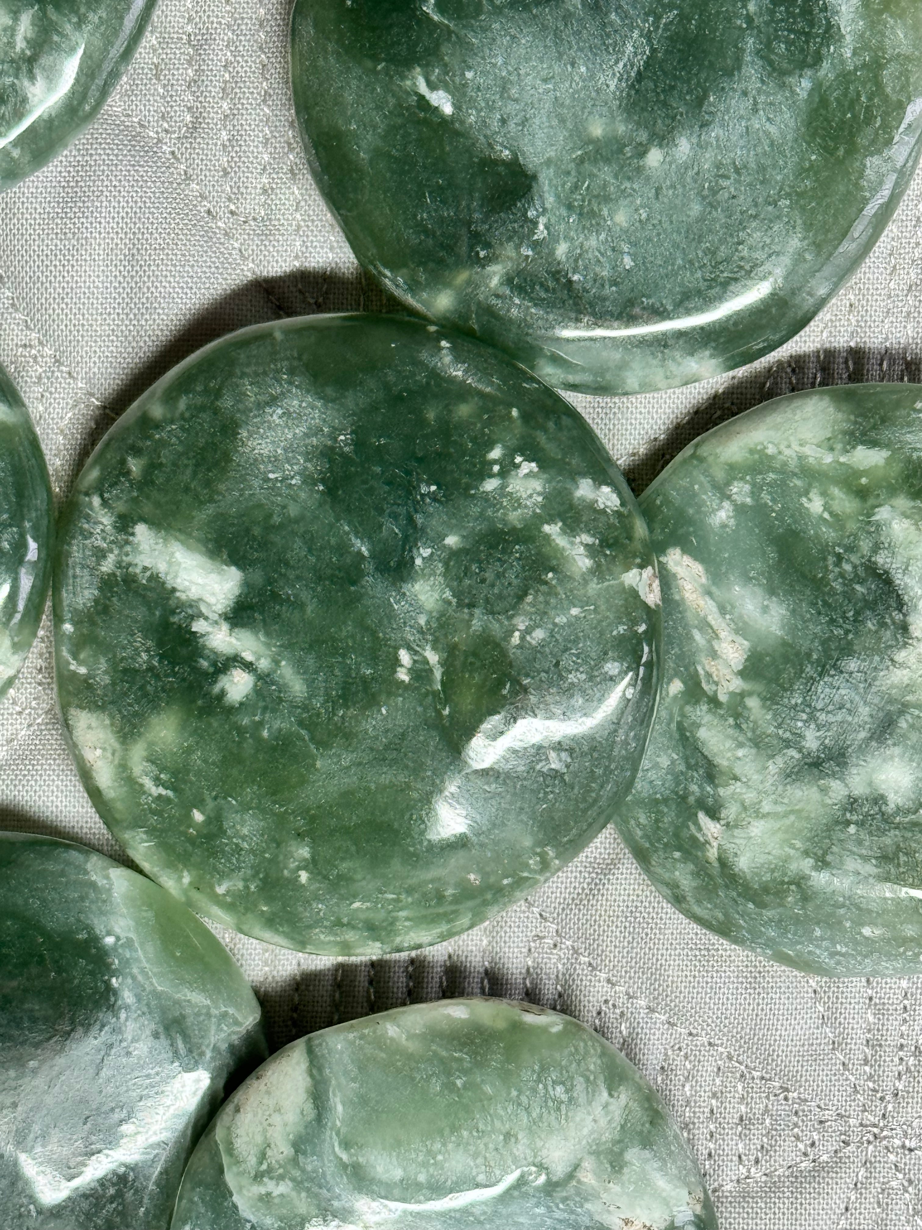 Green stone beads on a textured fabric background