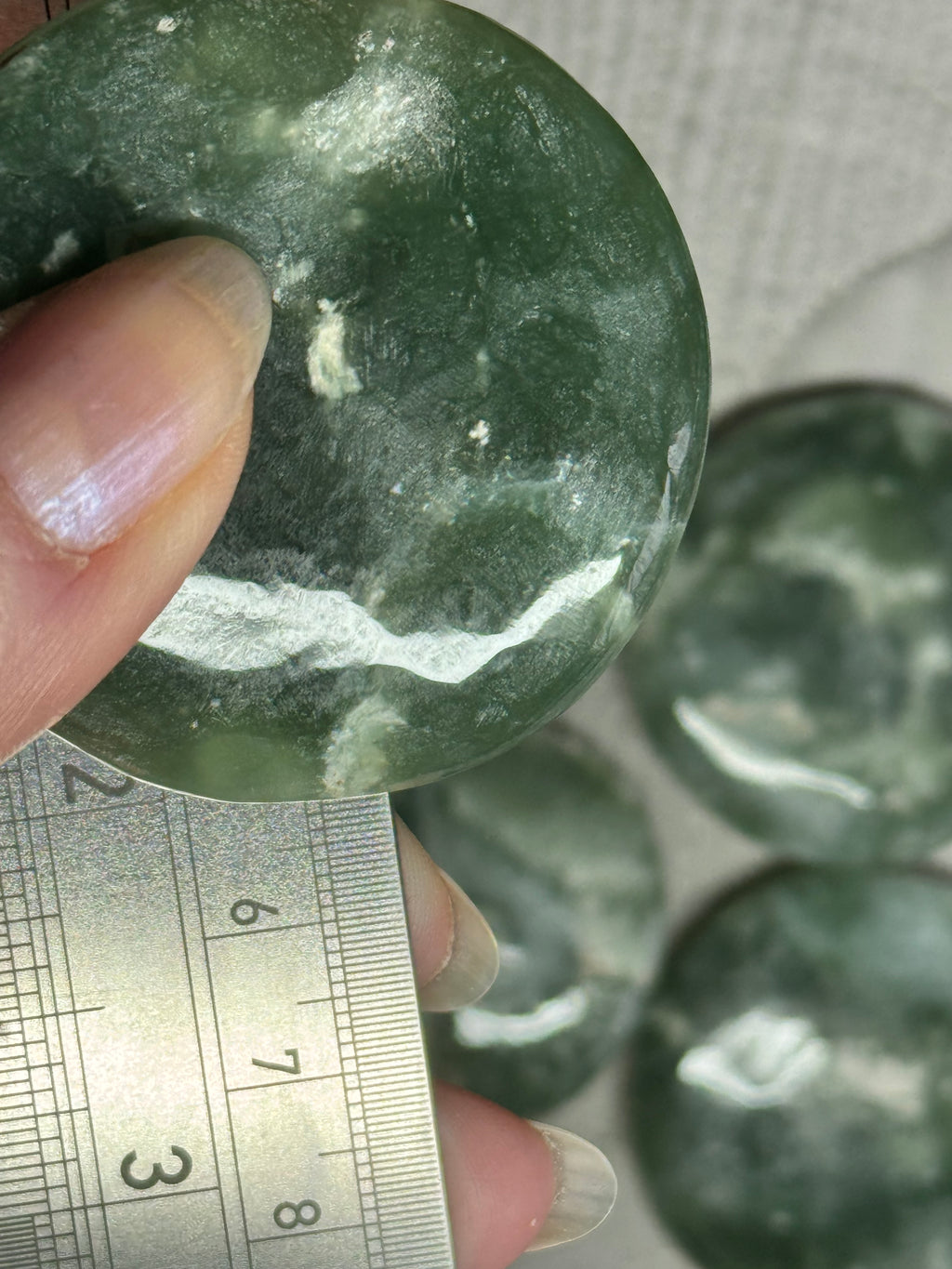 Green stone being held with a ruler for size reference